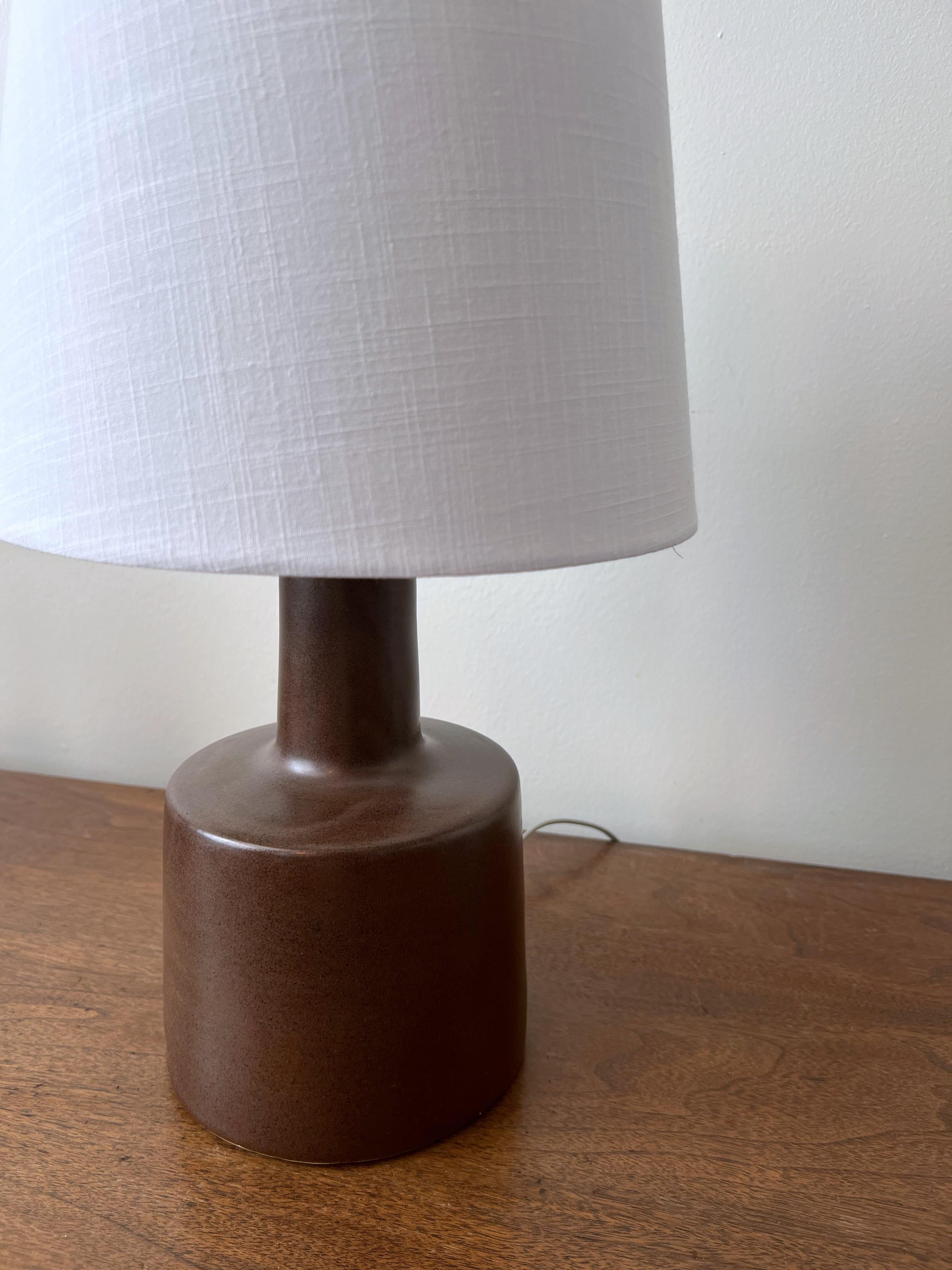 This minimalist organic table lamp is designed by the famed husband and wife duo, Jane & Gordon Martz. The color is a speckled earth tone brown with a lovely delicate aged patina. The base is signed. 

Jane & Gordon Martz works are highly sought