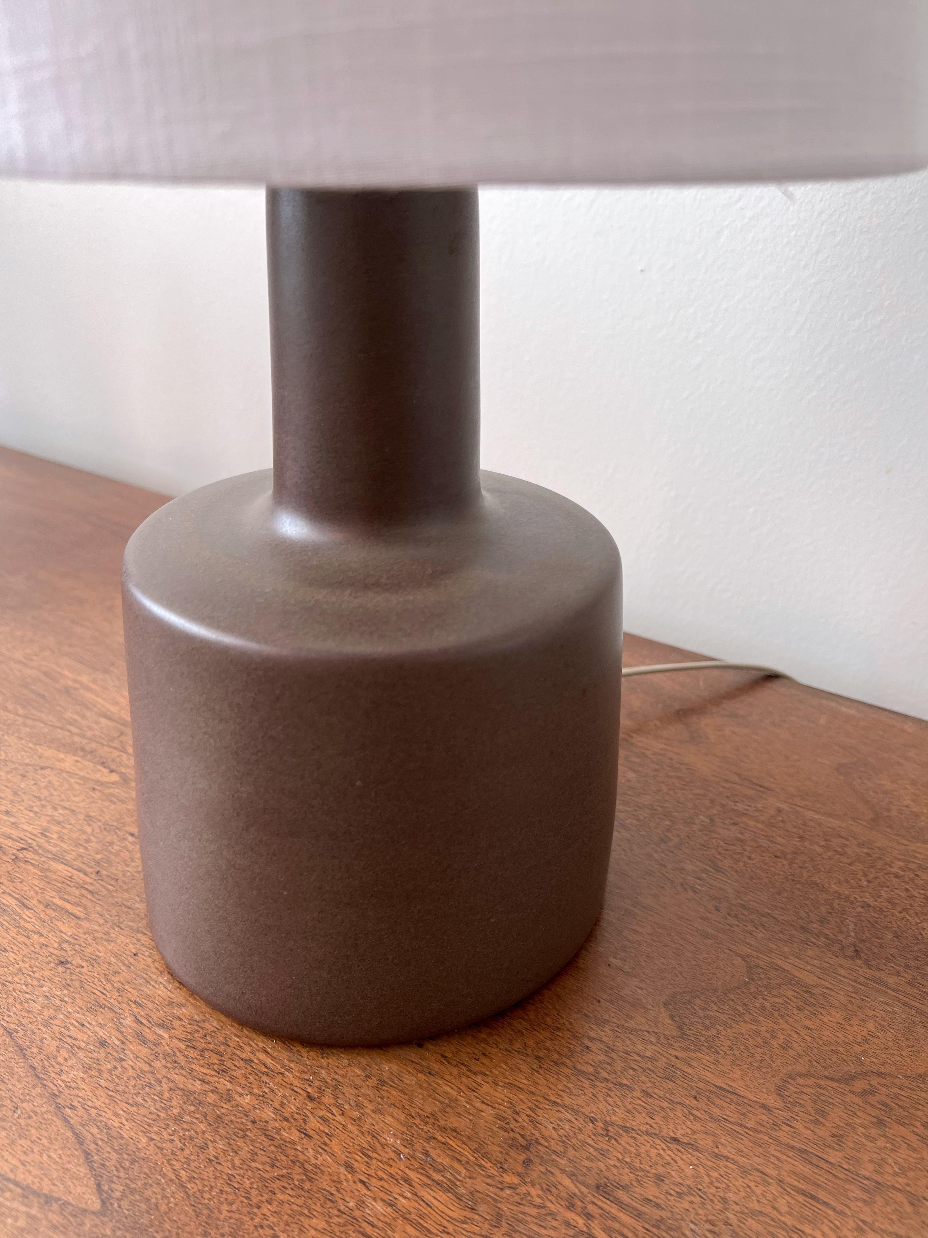 This minimalist organic table lamp is designed by the famed husband and wife duo, Jane & Gordon Martz. The color is a subtle speckled olive brown with a lovely delicate aged patina. The base is signed. 

Jane & Gordon Martz works are highly sought