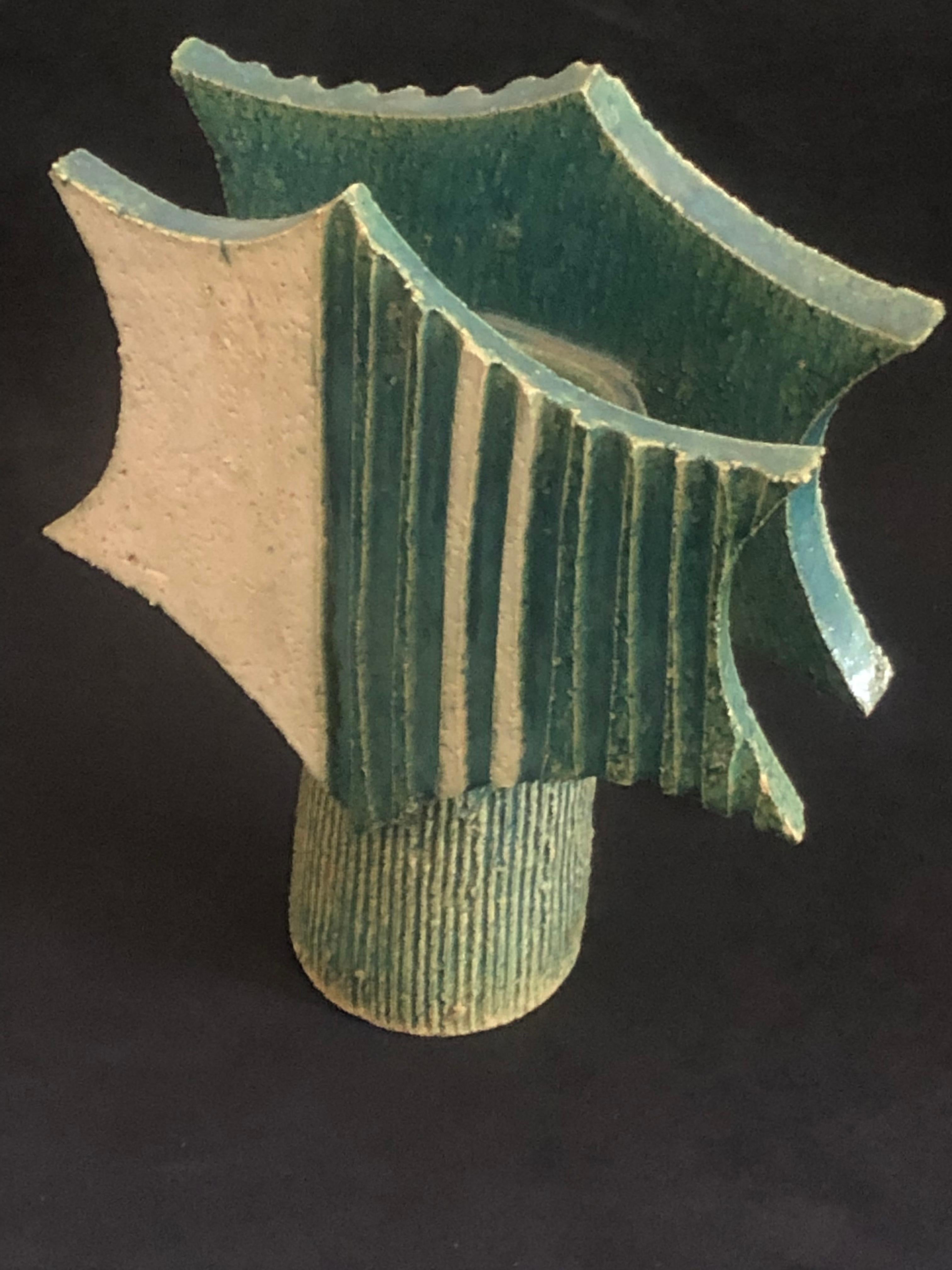 Eine Japanase Ikebana Studio Keramik Vase aus den 1960er Jahren.

Sternförmige Tafeln mit zentraler Zylindervase mit vertikalen Rillen, die mit einer cremefarbenen und grünen Glasur versehen sind.

Stempel 'Made in Japan' auf dem Sockel.

Ikebana