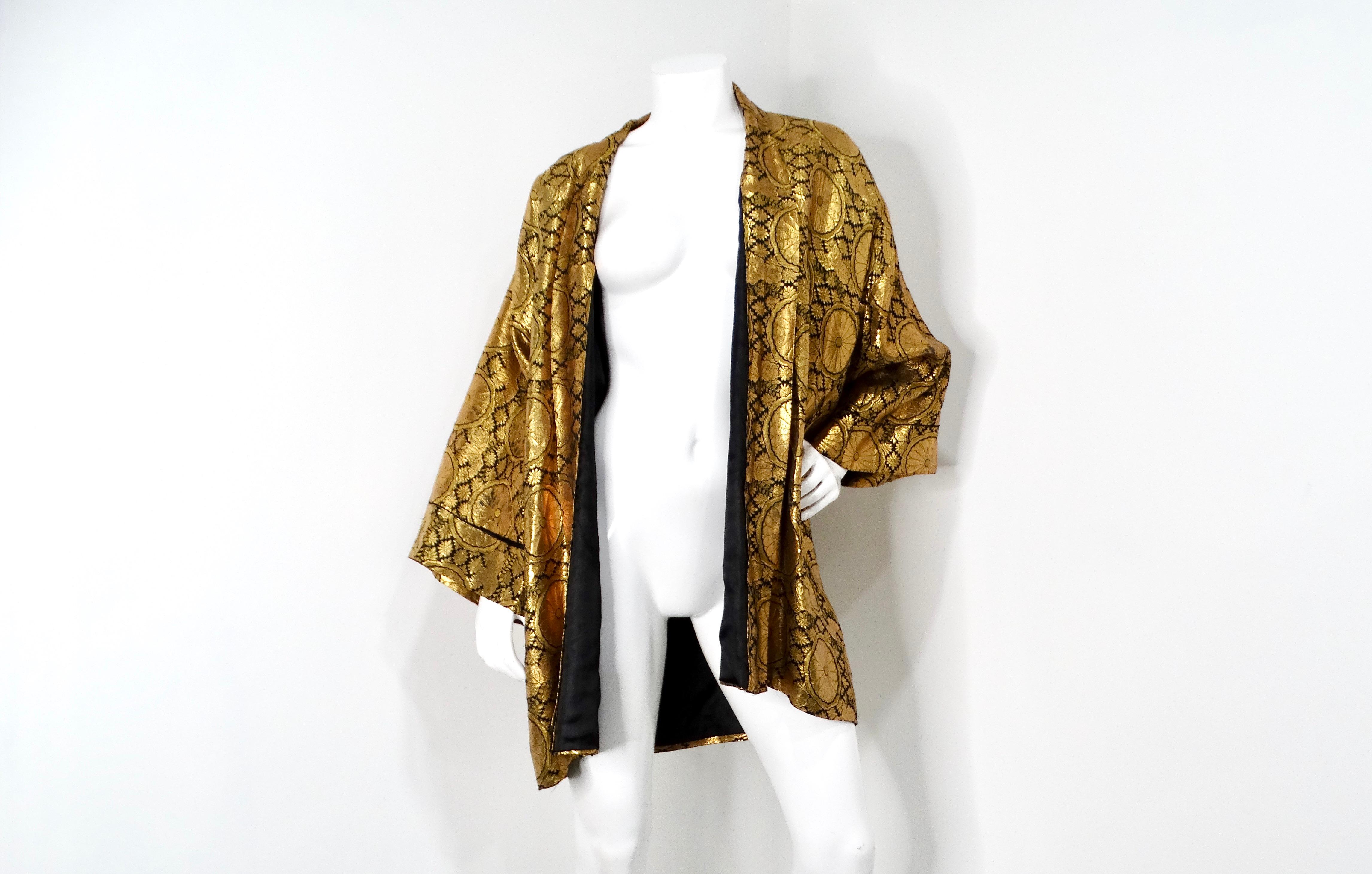 This stunning 1960s Japanese Black & Gold Metallic Floral Print Kimono Style Jacket is a striking addition to any fashion-forward wardrobe. The black base is beautifully adorned with an intricate metallic stitch flower print pattern, creating a rich