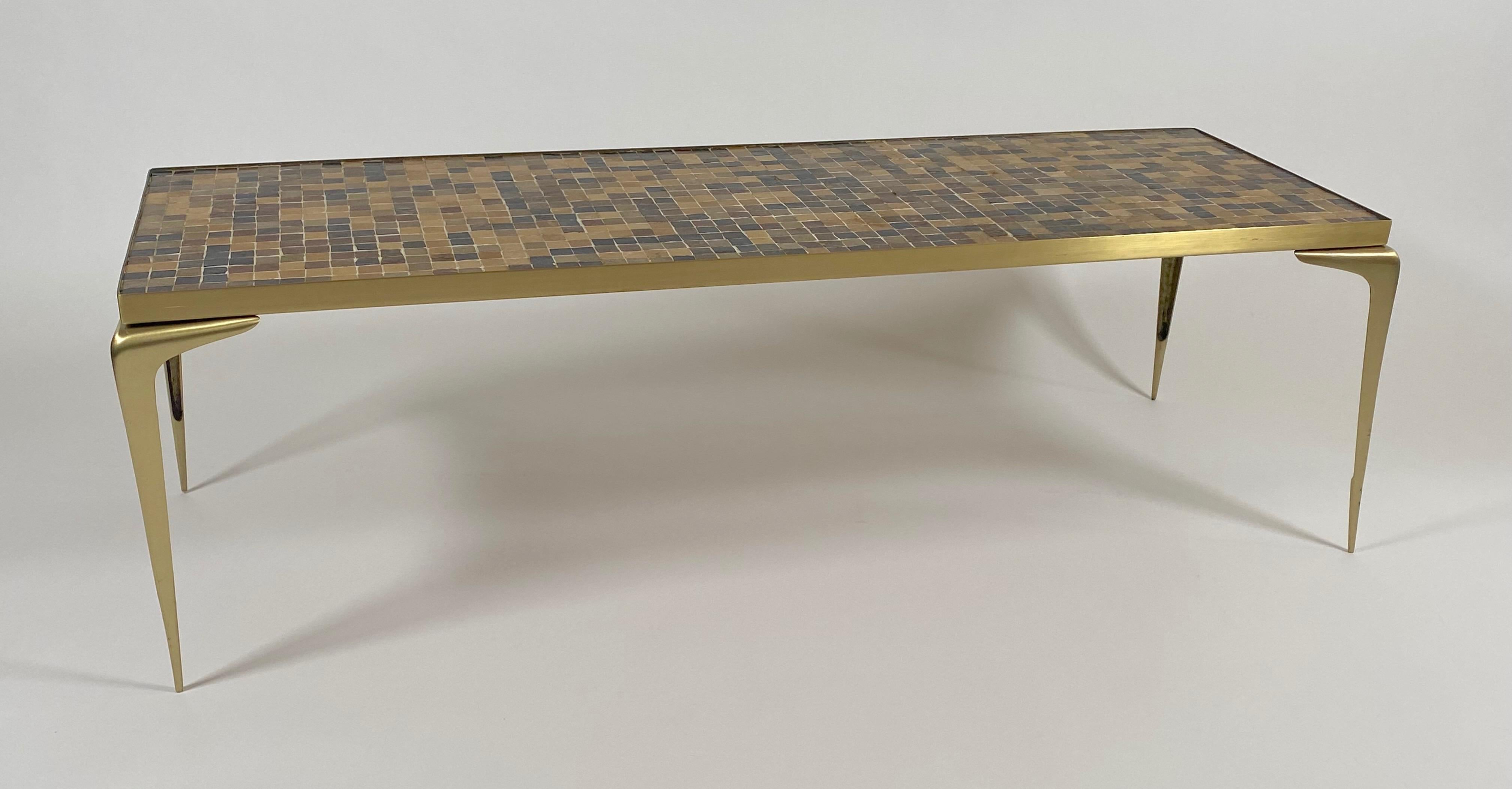 1960s mosaic and brass coffee from Japan, the mosaic is comprised of square glass tiles in various earth toned colors. The coffee table is constructed of solid brass with graceful slender curved legs with pointed ends, the shape is a somewhat narrow