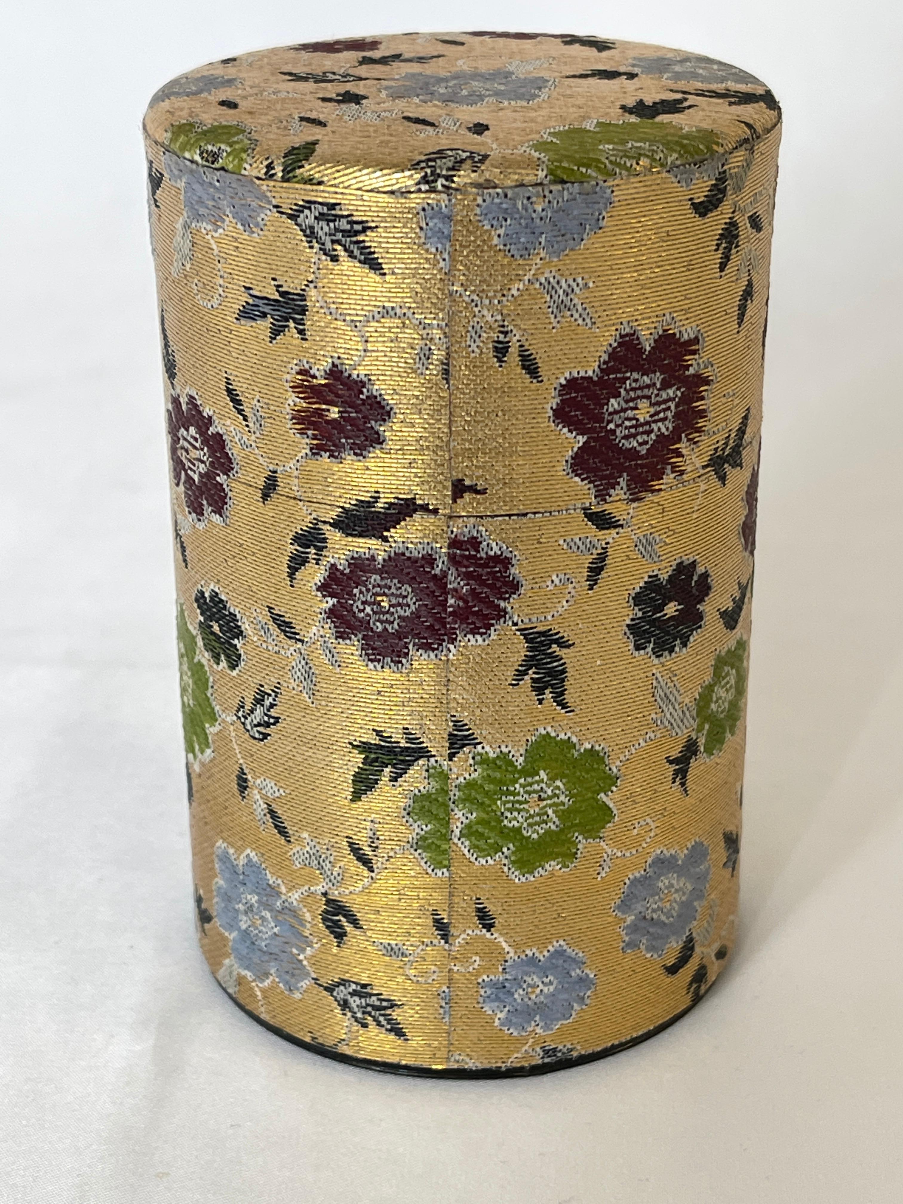 Porta tè in latta degli anni '60 rivestito in tessuto tradizionale giapponese intrecciato in oro con motivi floreali. Ci sono due coperchi, uno interno e uno esterno, per mantenere fresche le foglie di tè.