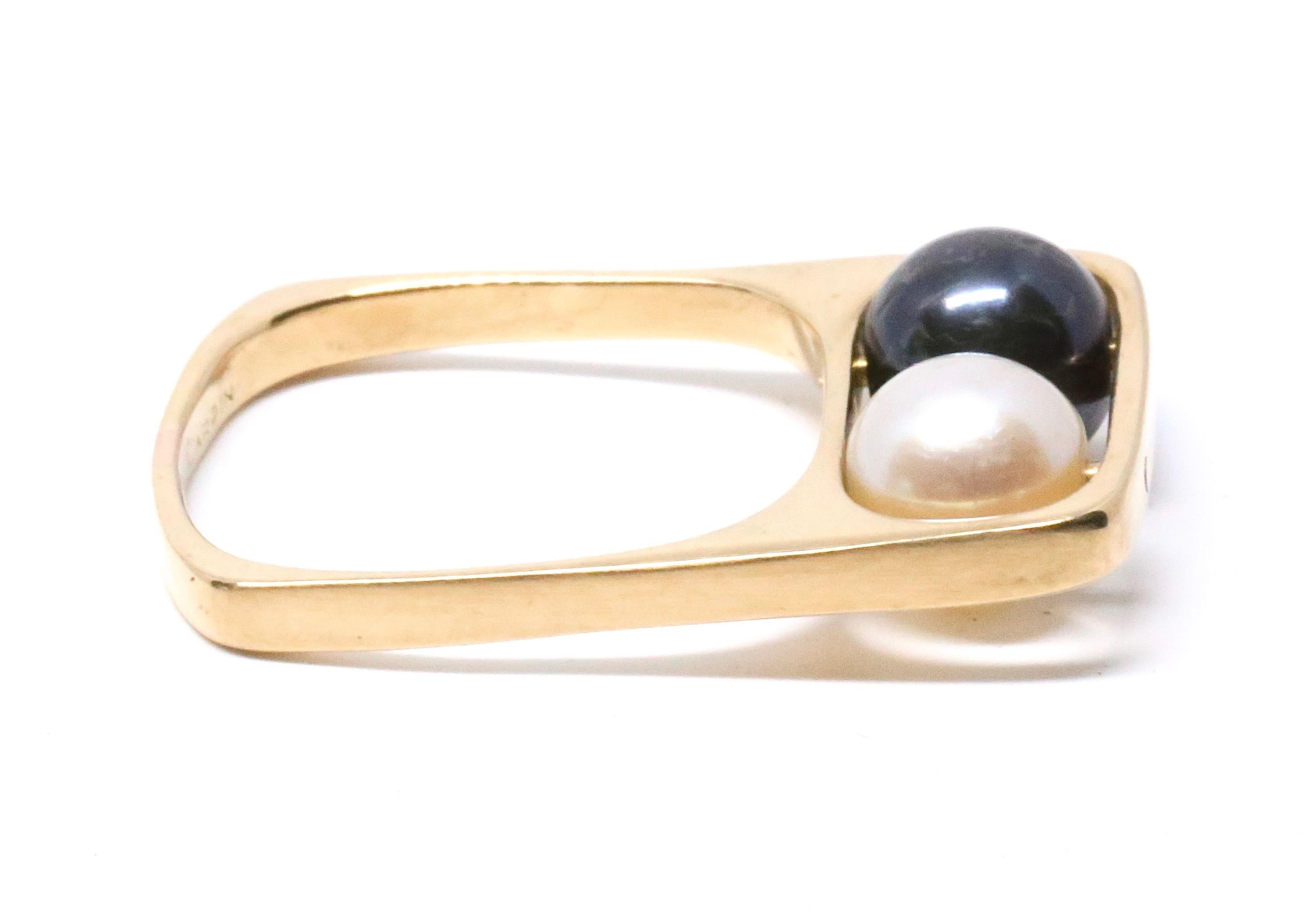 Very rare and important 18k yellow gold ring set with movable pearls designed by Jean Dinh Van for Pierre Cardin dating to the 1960's. The design features a squared shank with an open which encloses two 7.0mm pearls. The pearls are drilled and
