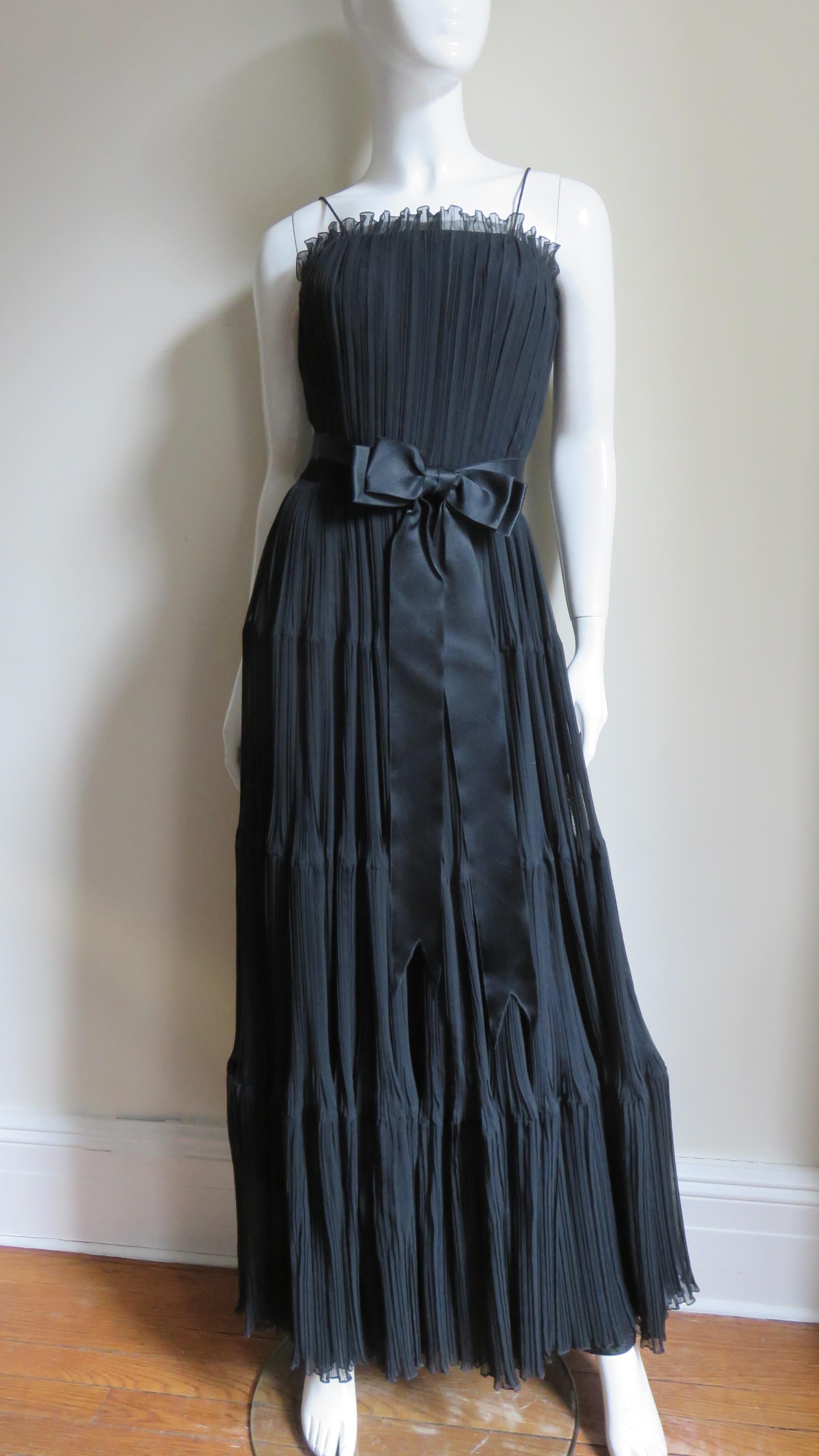 Ein schwarzes Kleid mit Mikrofalten aus Seide von Jean Louis. Das Kleid hat ein tailliertes Mieder mit einem entbeinten Innenkorsett, Spaghettiträger und einen langen, vollen Rock mit 4 Stufen.  Es ist vollständig mit schwarzer Seide gefüttert, hat