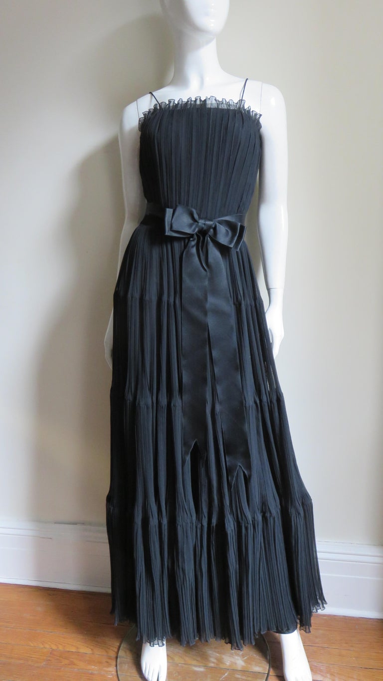 A black silk micro pleated gown from Jean Louis. The dress has a fitted bodice with a boned inner corset, spaghetti straps and the long full skirt is comprised of 4 tiers.  It is fully lined in black silk, has a back zipper and the waist is