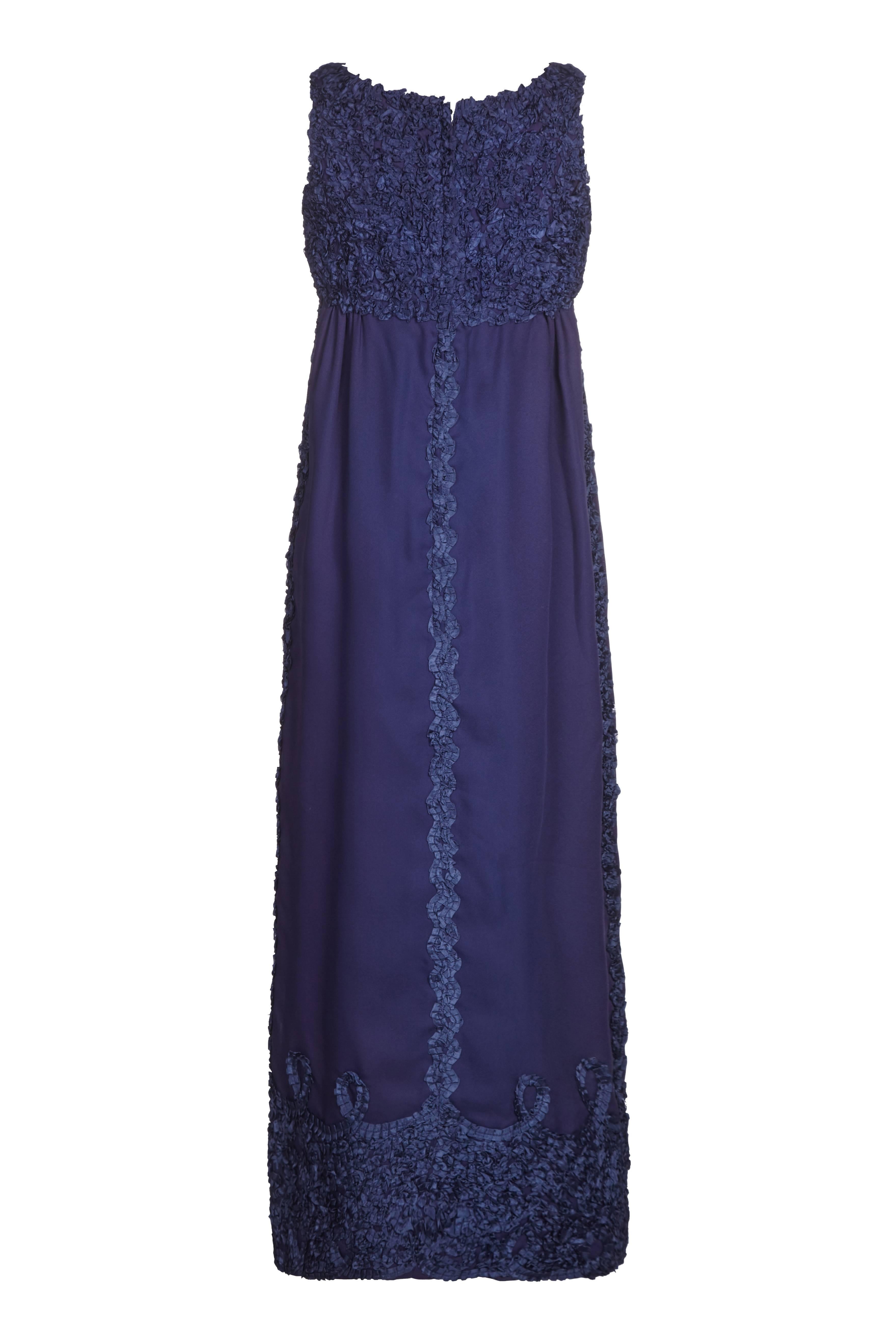 This attractive Jean Varon 1960s Midnight Blue evening gown is a sophisticated departure from the designer's trademark space-age style pieces, and has a softer, more feminine focus. The dress is sleeveless, with a classic Empire-Line cut that falls