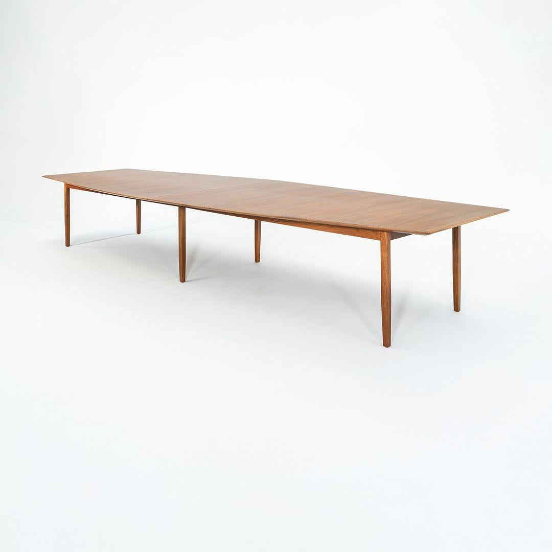 Il s'agit d'une table de conférence ou de salle à manger en noyer du groupe 8, conçue par Jens Risom et produite par sa société Jens Risom Design/One. Elle présente un plateau ovale en placage de bois bicolore qui repose sur une structure en noyer à