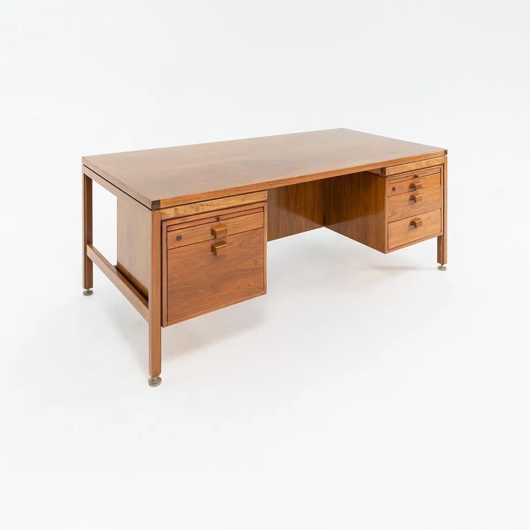 This is an executive desk in walnut, designed by Jens Risom for Jens Risom Designs in the 1960s. It features two drawers on the left, three drawers on the right, and pull-out surfaces on each side. It retains its Jens Risom Design tag inside of a
