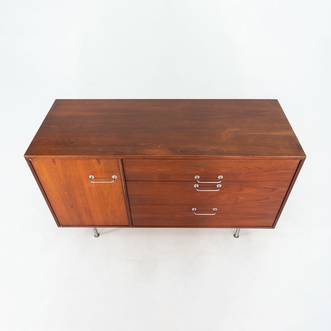 This is a walnut credenza, designed by Jens Risom and produced by his company, Jens Risom Designs. It was handcrafted in the USA in the 1960s. It has a beautifully grained walnut case, with several drawers and storage spaces. It has brushed steel