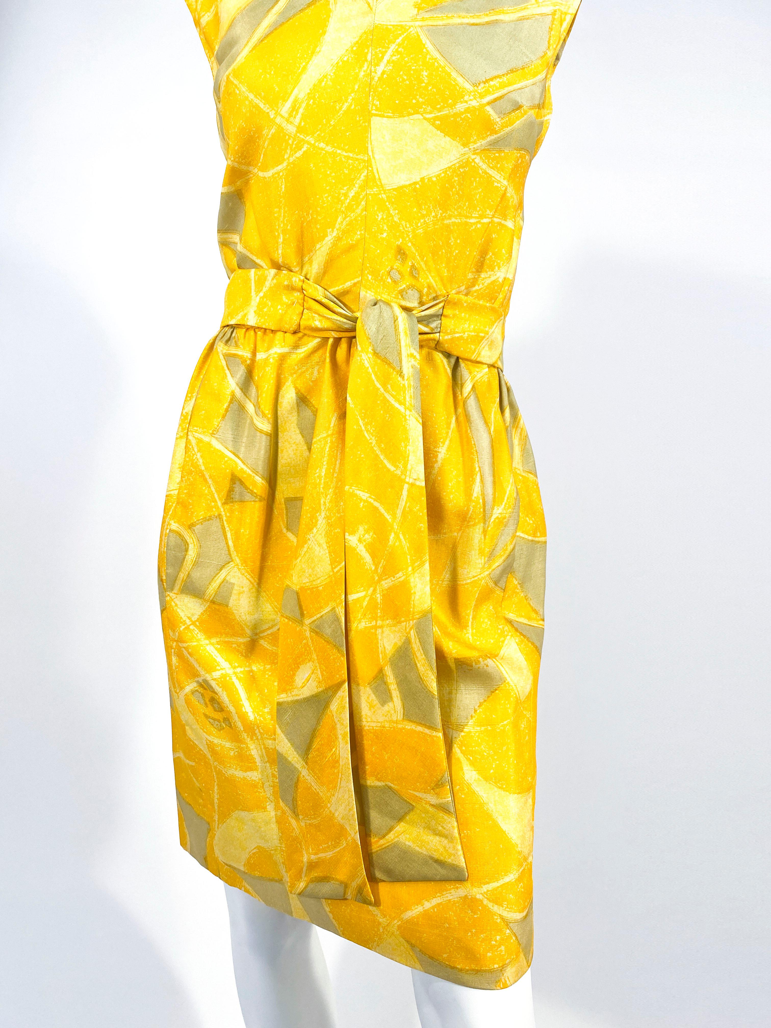 1960s Shannon Rodgers for Jerry Silverman abstract printed sheath dress in hues of yellow, soft golds, and light avocado. The sash belt is attached in the front where it ties while the back has snaps to secure the dress closed. The back also has a