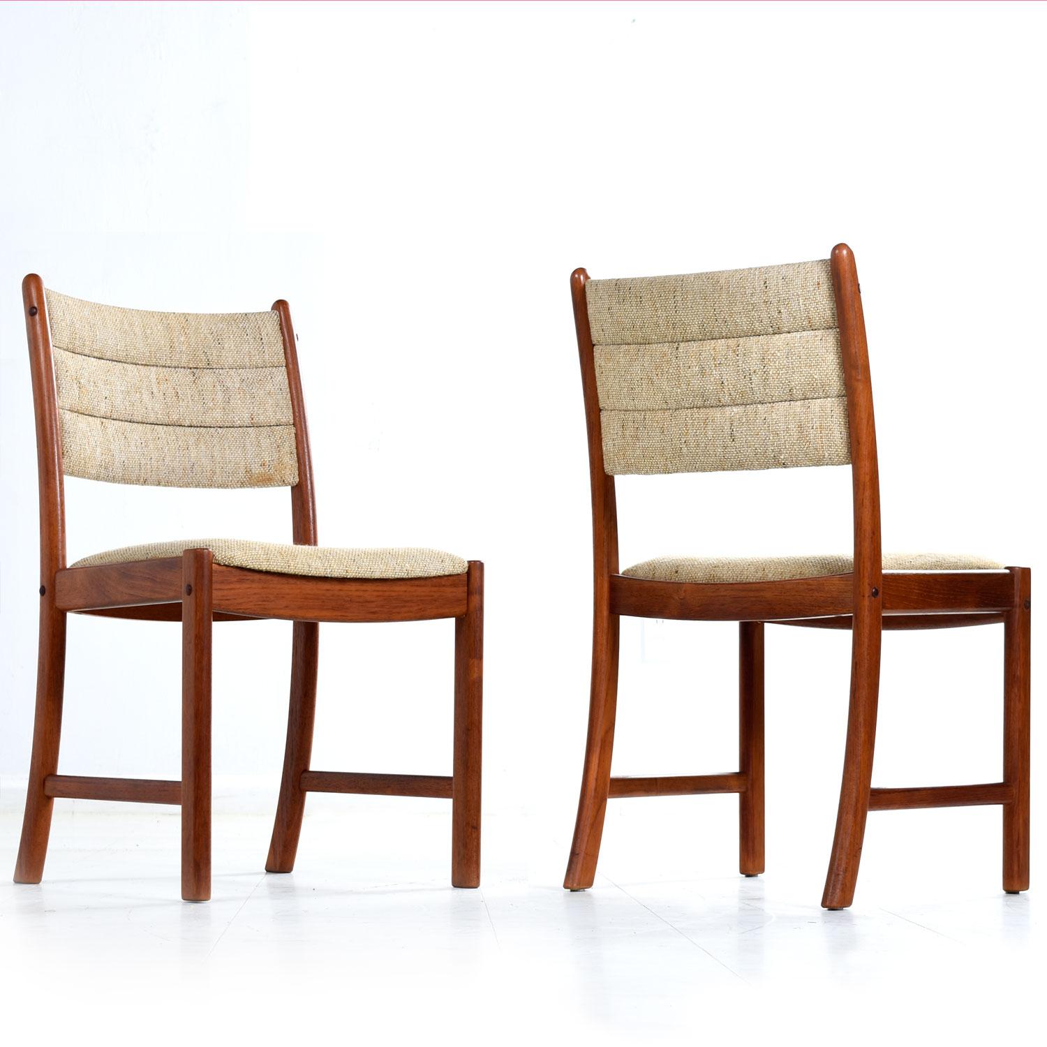 A set of ten solid teak dining chairs by Johannes Andersen for Uldum Møbelfabrik. The several decades old solid teak has a rich amber patina that bounces beautifully against the original wool fabric. The low back profile features two rows of