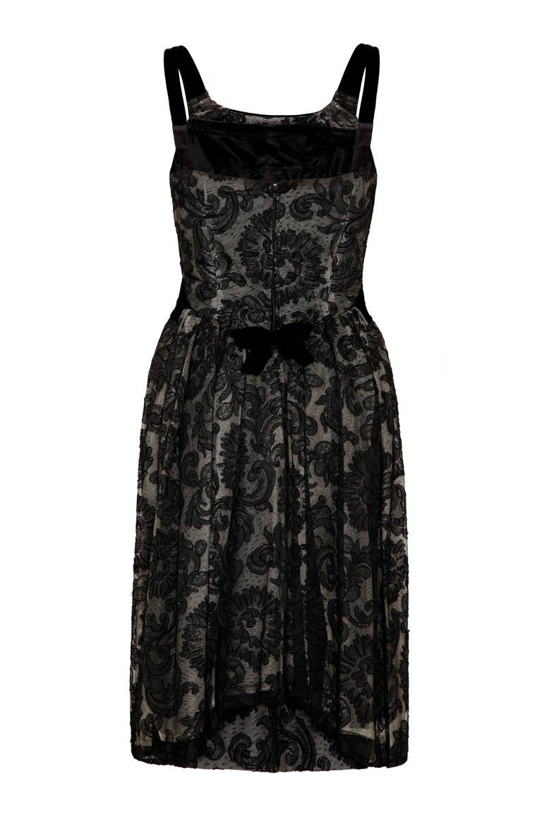This incredible 1960s black lace and velvet cocktail dress is couture from British designer John Cavanagh, who was renowned for his understated, elegant designs and often created pieces for the Royals during this period. The dress is comprised of