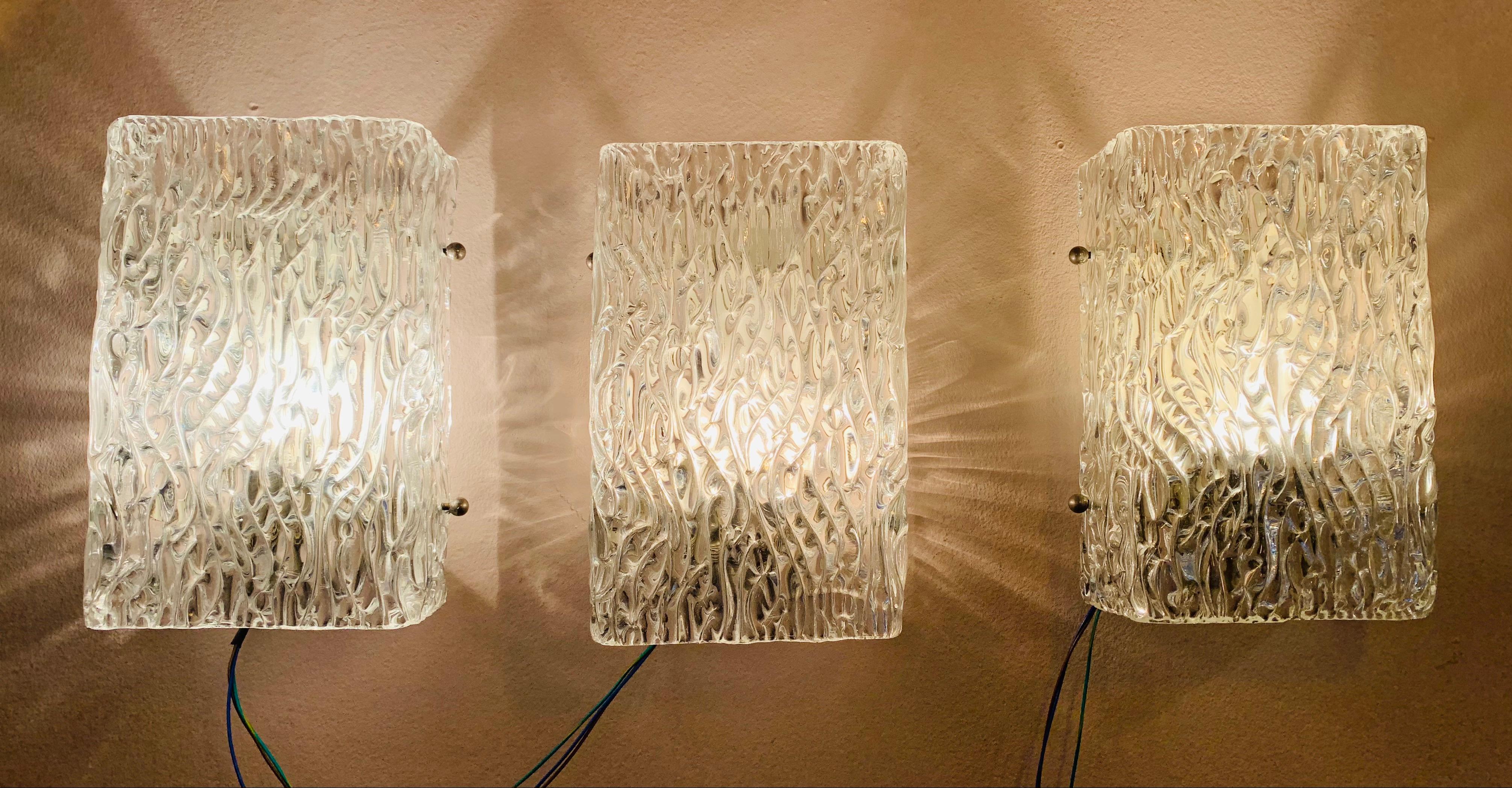 1960s wall lights or sconces designed by J.T. Kalmar and manufactured by Kalmar Lighting in Vienna, Austria. The sculpted, textured, moulded glass has a vertical wave pattern which produces a warm diffused light. The rectangular shade has glass on