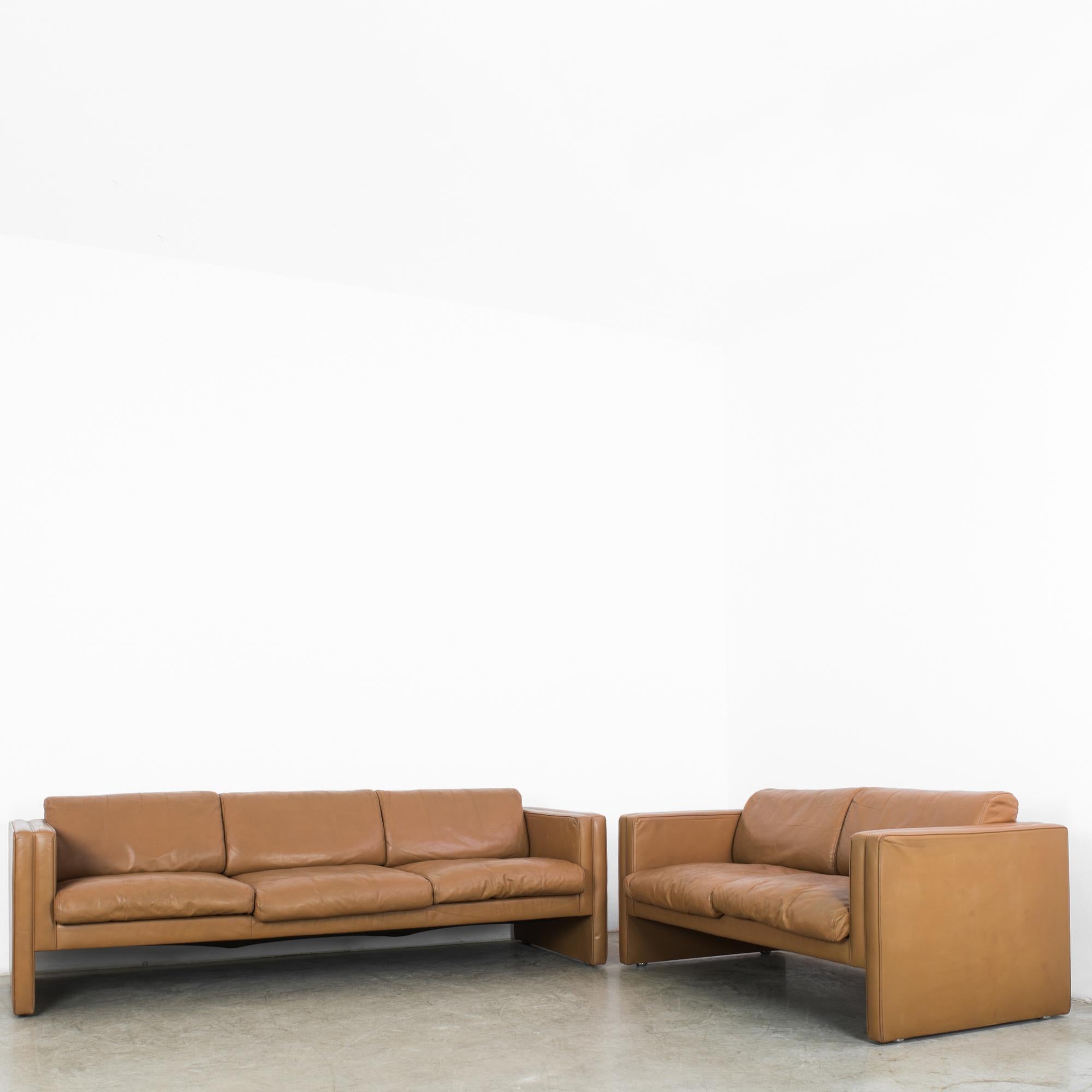 A pair of 1960s leather sofas by Danish furniture designers Knoll. A Mid-Century Modernist silhouette in camel-colored leather. The light frame is composed of clean, straight lines; the cushions are ample and deep. Included are one three seat sofa,