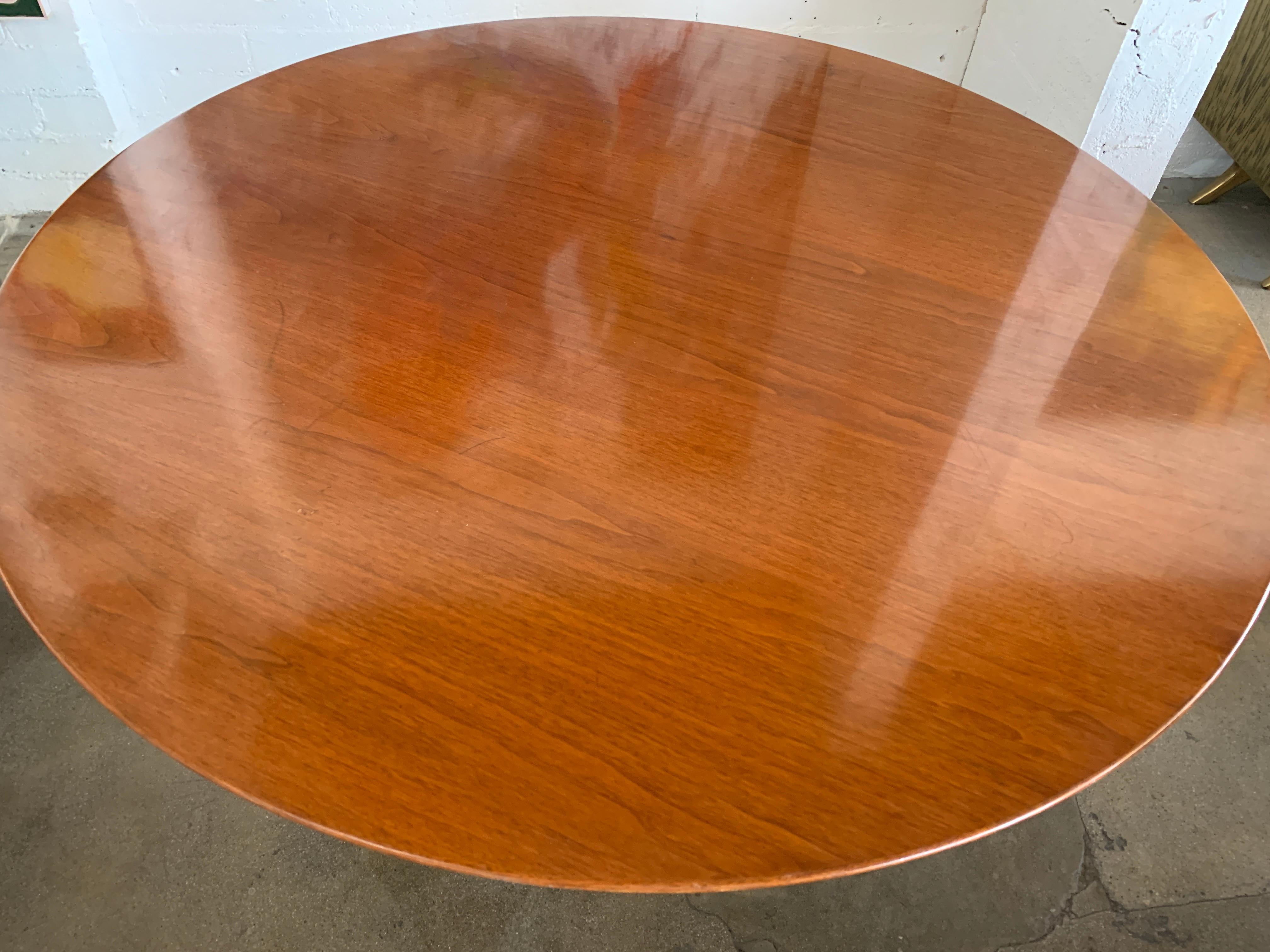 A vintage knoll Saarinen tulip table with a walnut top. It bears a vintage Knoll label that dates it to the 1960s as the address reads 320 Park Avenue. It is 54 inches in diameter and 28.25 inches tall. The top is quite lovely with age appropriate