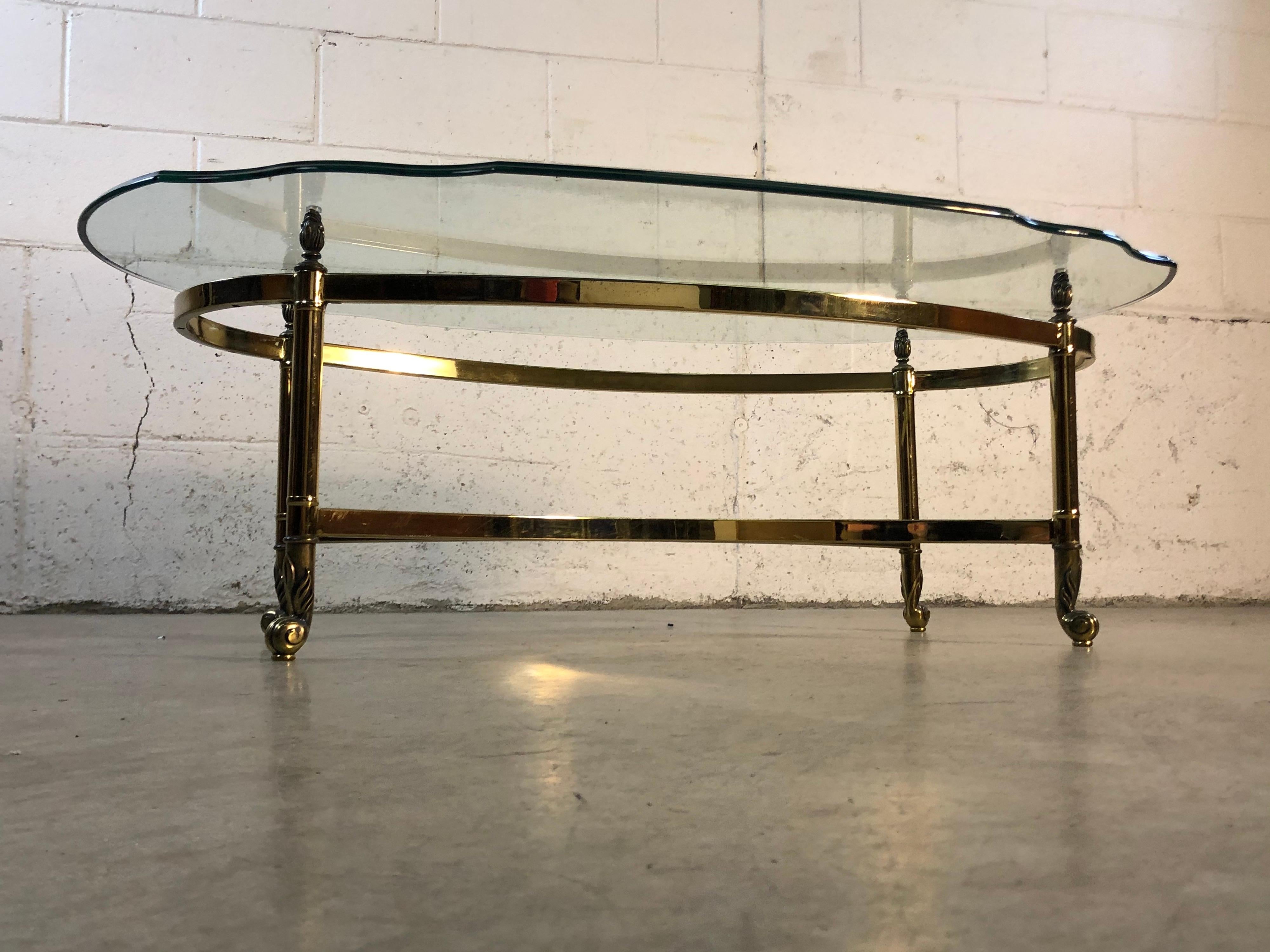 Vintage 1960s oval brass and glass coffee table by La Barge. The table has scroll accented feet and a scalloped glass top with beveled edge. No marks.