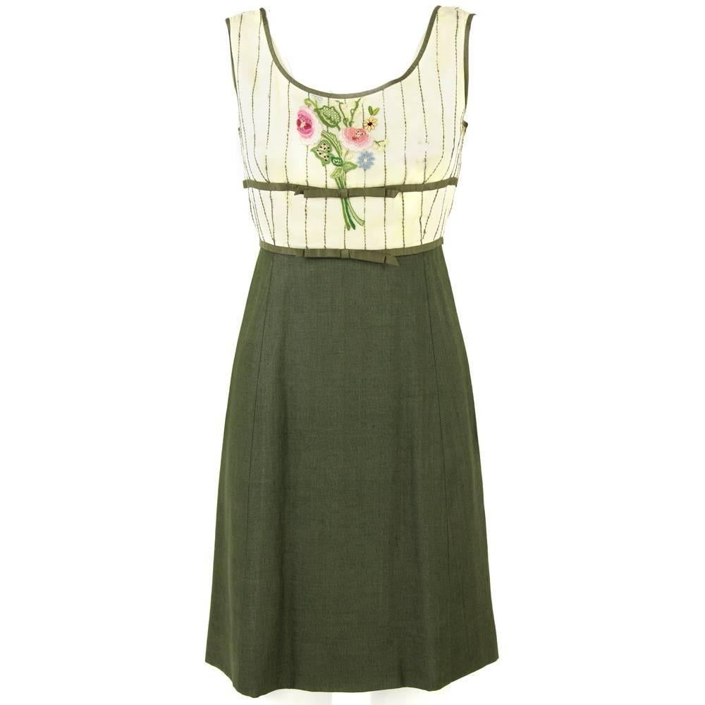 Designed by the Italian fashion house La Duchesse de Paris in the 1960s, this cute sleeveless polyester day dress features a vest matching the military green of the skirt and details. A multicolor floral embroidery on the chest and the front green
