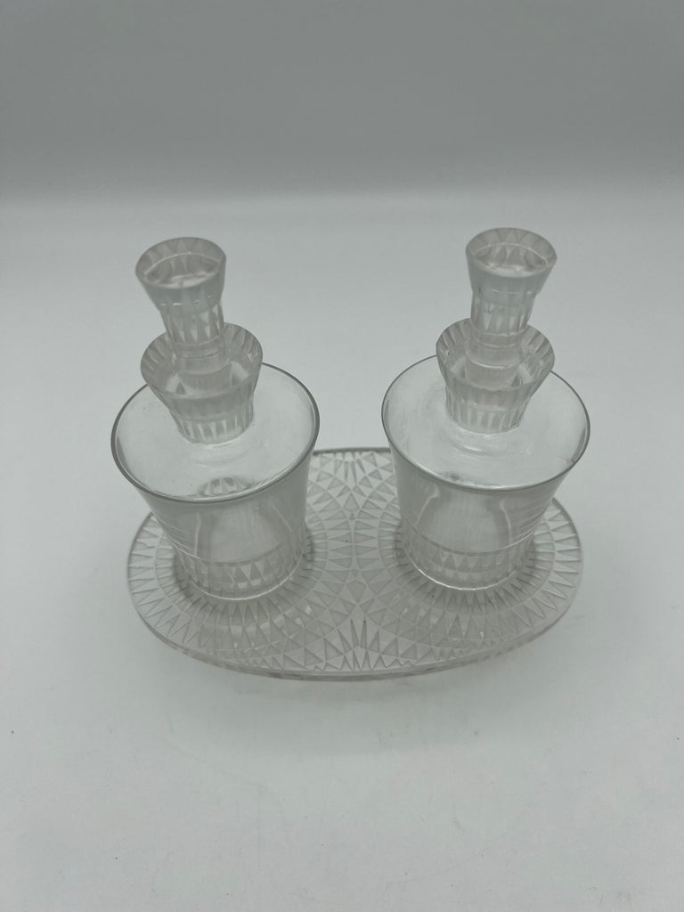 The set is made out of hand cut crystal, featuring geometric pattern. The bottles come with the matching stand. Signed Lalique. 
Bottle size is 5.5”H x 2.25”W.
The stand size is 5.75”L x 3.5”W x 1.5”H.