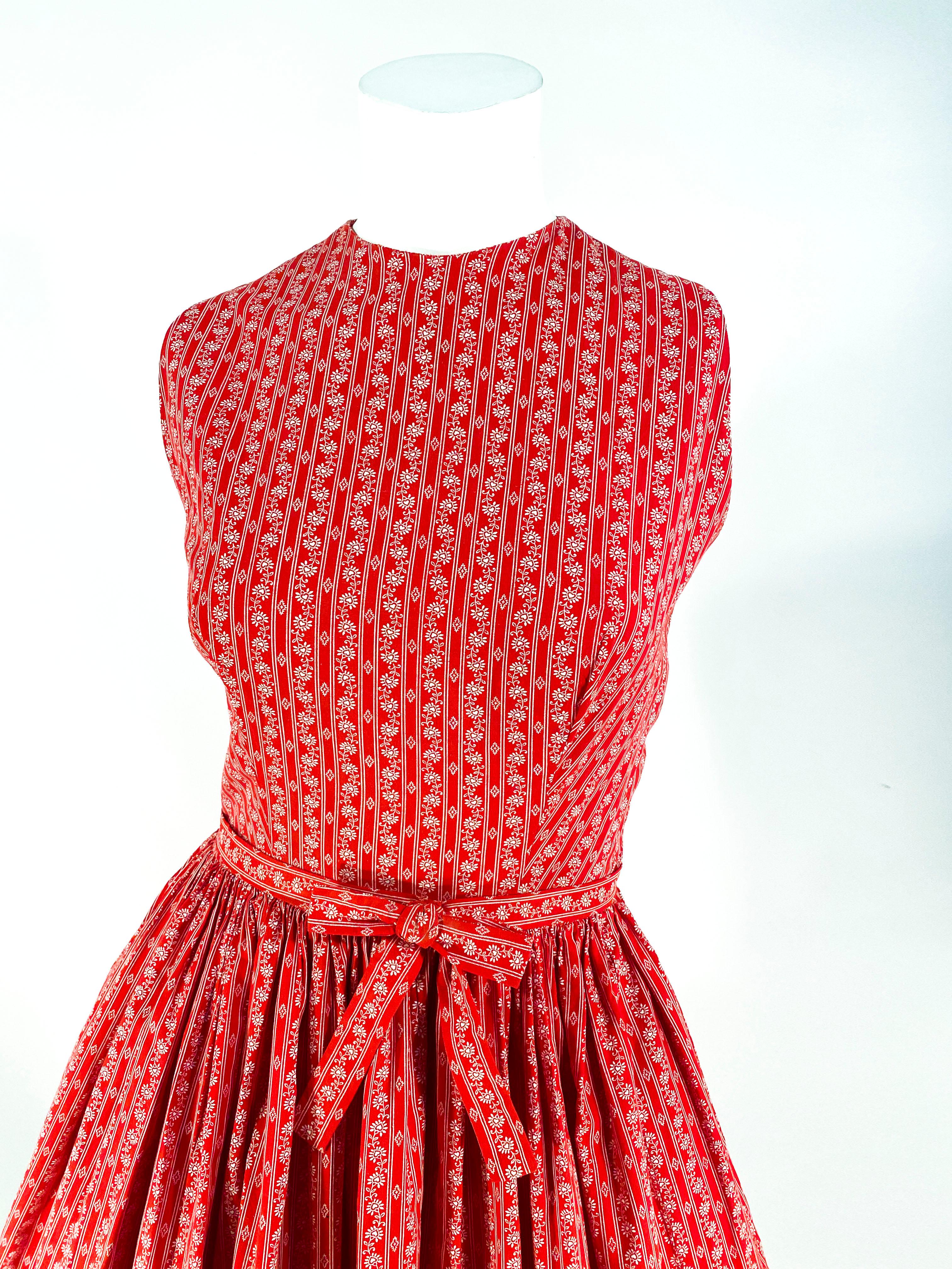 1960s Lanz red cotton dress featuring a fine calico print with heart-centered flowers, fitted sleeveless bolide, high neckline, keyhole back, seashell button closure on back of dress, and a gathered full skirt. This dress has been styled and