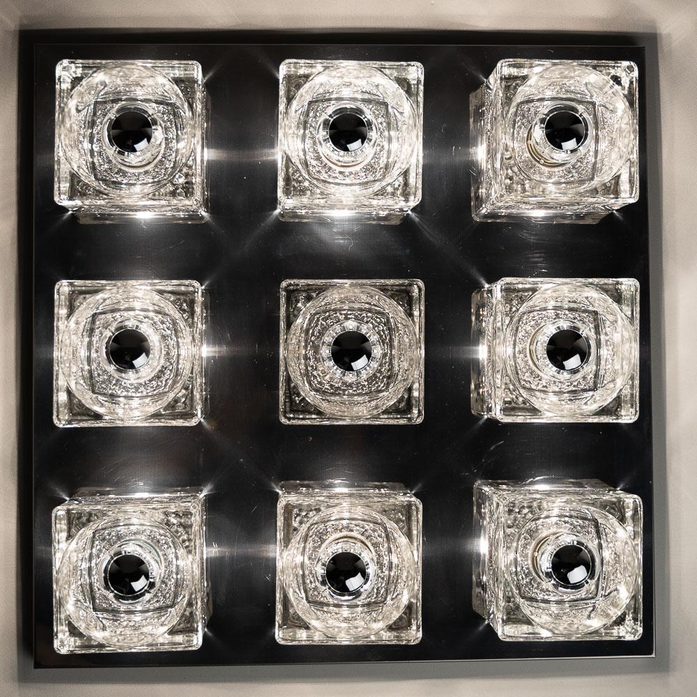 Square table light attributed to Peil & Putzler consists of a chrome plate base and nine solid glass Whiskey shaped glasses. 
Weight of this feature = 15,35 kilo and it holds 9 x E14 bulbs