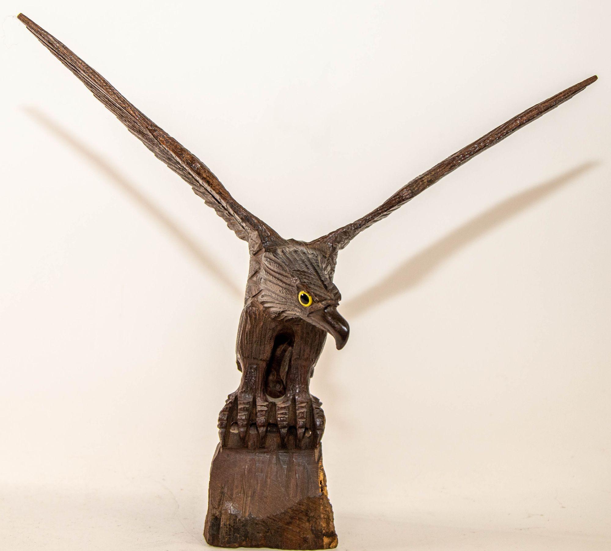 A large hand-carved iron wood eagle perched on a tree stump and surveying the surroundings ready to fly.
Hand carved wood vintage extremely detailed bald eagle perched upon rockery with glass eyes.
Hand carved Ironwood Southwestern seri sculpture