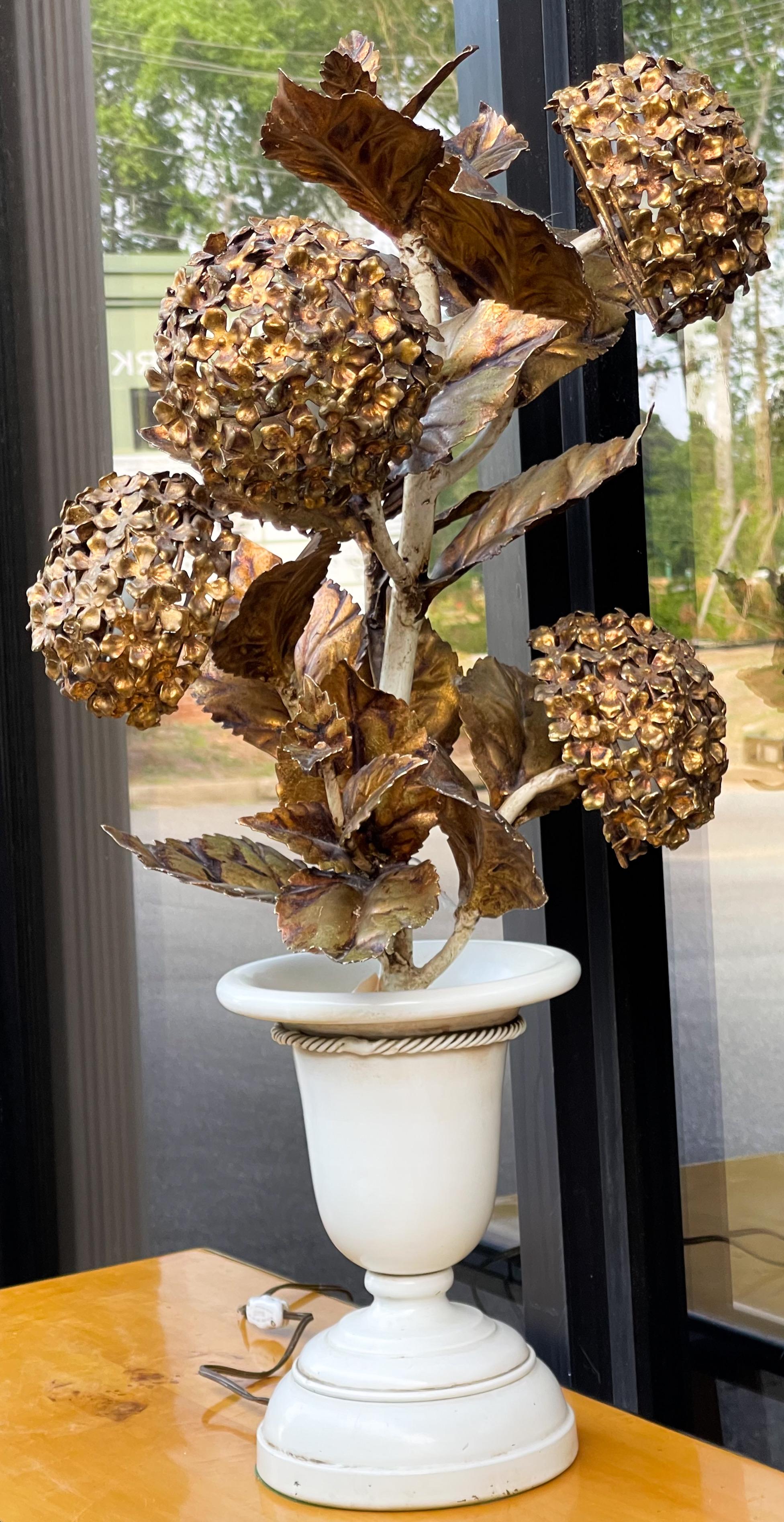 This is a unique piece! It is a large Italian gilt metal tole table lamp with a hydrangea plant in a planter. It dates to the 60s and is in working order.