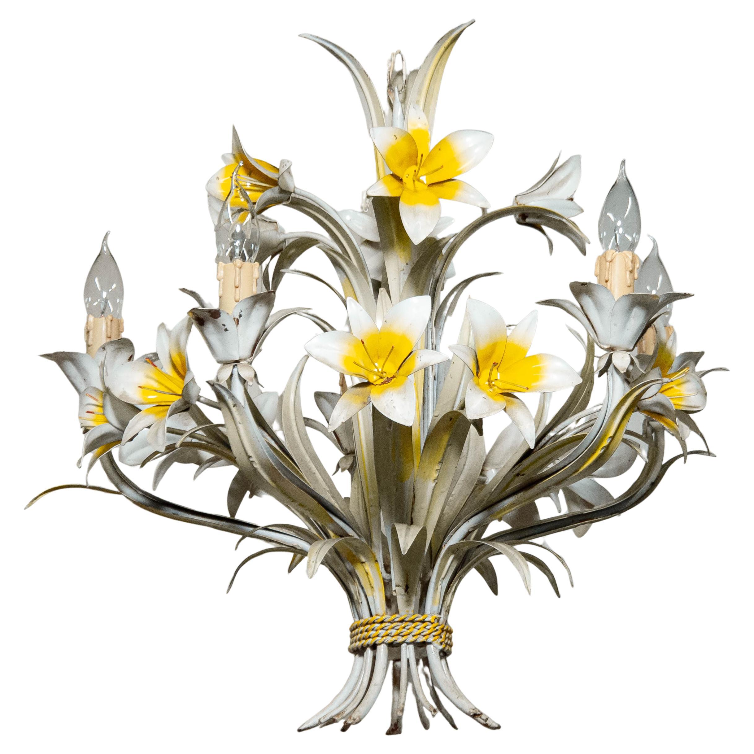 Affascinante lampadario a tole italiano degli anni '60 con un'esuberante esposizione di gigli fatti a mano. Realizzato interamente in metallo verniciato, questo lampadario floreale incarna lo spirito romantico e decorativo del design italiano di