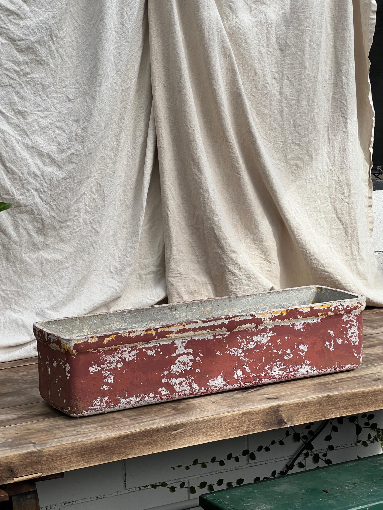 Crafted by willy guhl in switzerland during the 1960s, these rectangular concrete box planters exhibit a weathered rich red paint, adorned with a beautifully aged patina.

Measurements: 31
