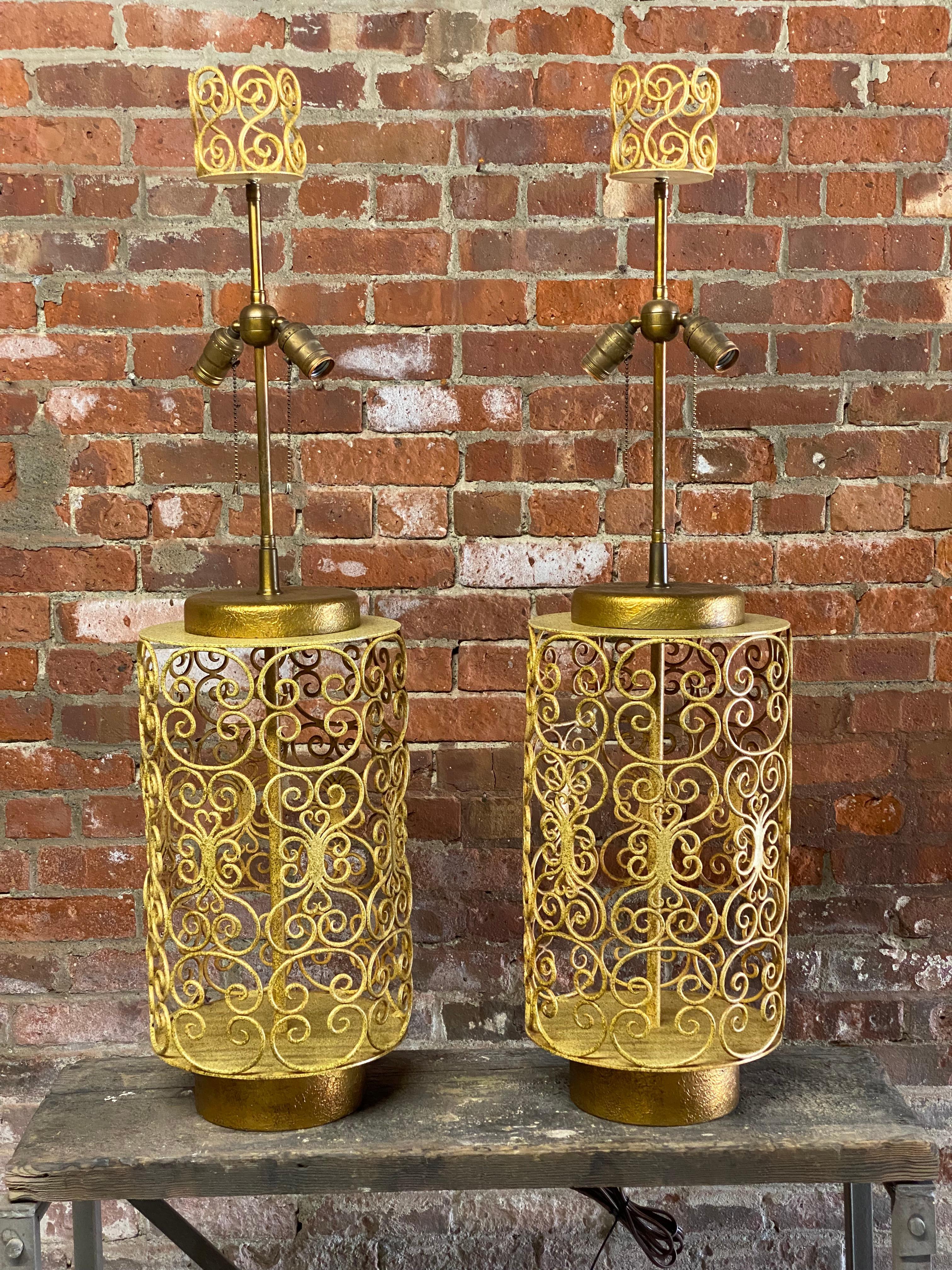 Very large and beautiful pair of decorative scrolled metal work table lamps. Textured gold painted caps and bases. The metalwork is a spatter paint enamel. Double bulb sockets. The finials are a handful! Circa 1960. Old working wiring. Good overall