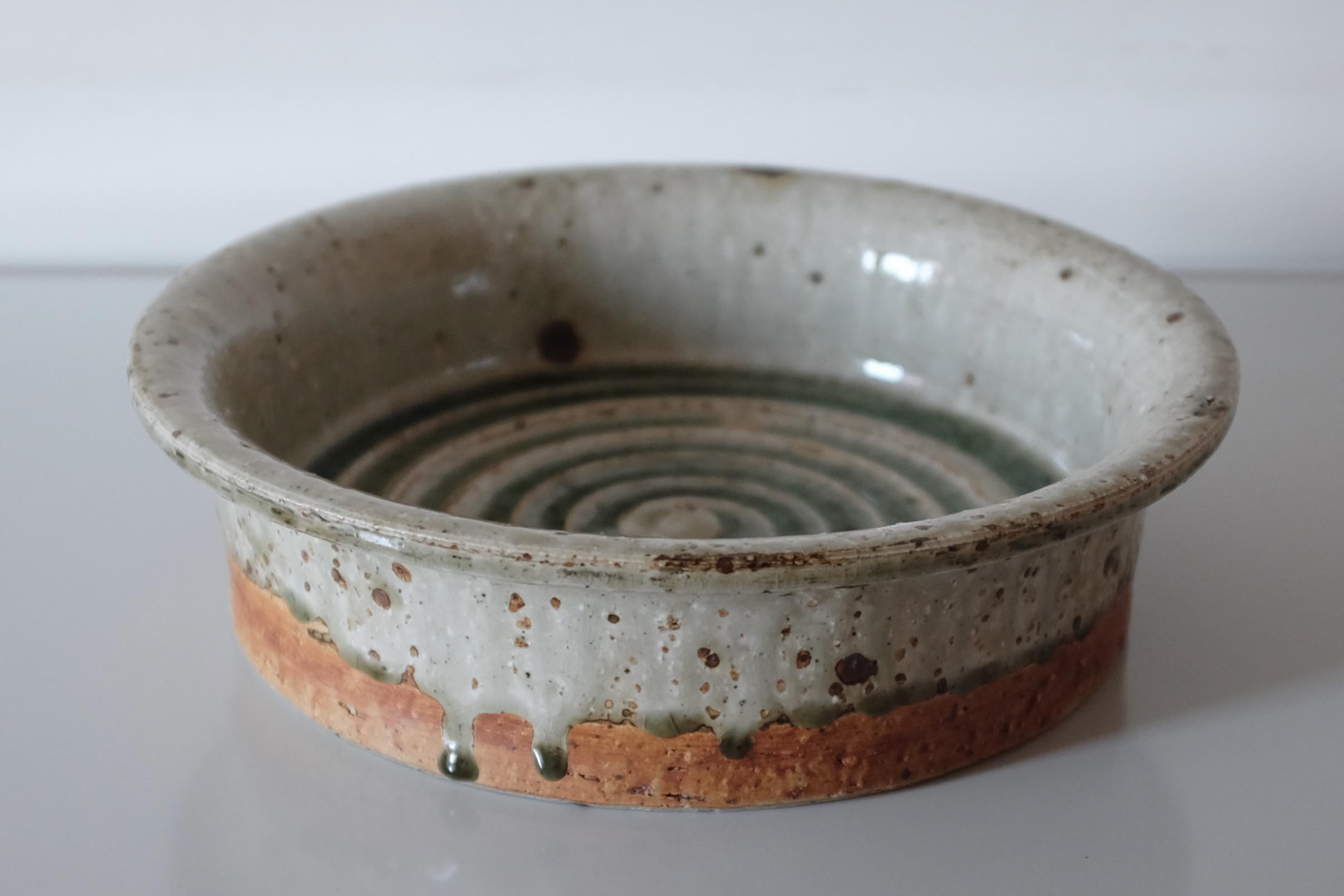 Splendido piatto di grandi dimensioni in gres lavorato a mano dall'artista svedese Marianne Westman, risalente agli anni '60. All'interno c'è una forma a spirale in una splendida glassa verde che cola sui lati del piatto. Realizzato presso l'Ateljé