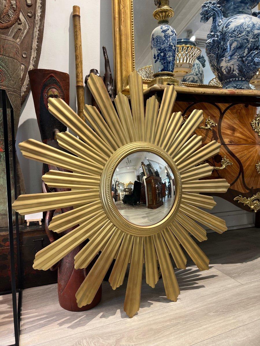 Wir präsentieren Ihnen diesen einzigartigen und großen konvexen Hexenspiegel in Sonnenform.  Dieser Spiegel mit einem Durchmesser von 90 cm ist aus gebogenem und vergoldetem Metall gefertigt, das Verzerrungseffekte erzeugt. Es stammt aus der Mitte