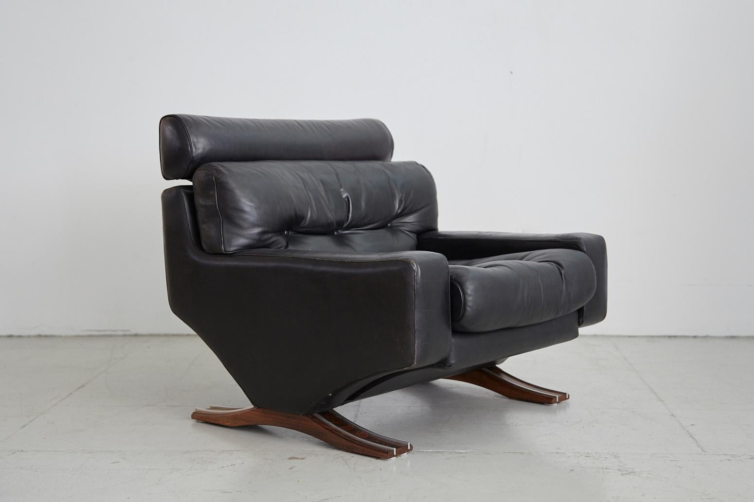 Handsome Italian leather armchair with original black leather cushioned seat resting on rosewood and aluminum legs. Great tufting detail and extremely comfortable.