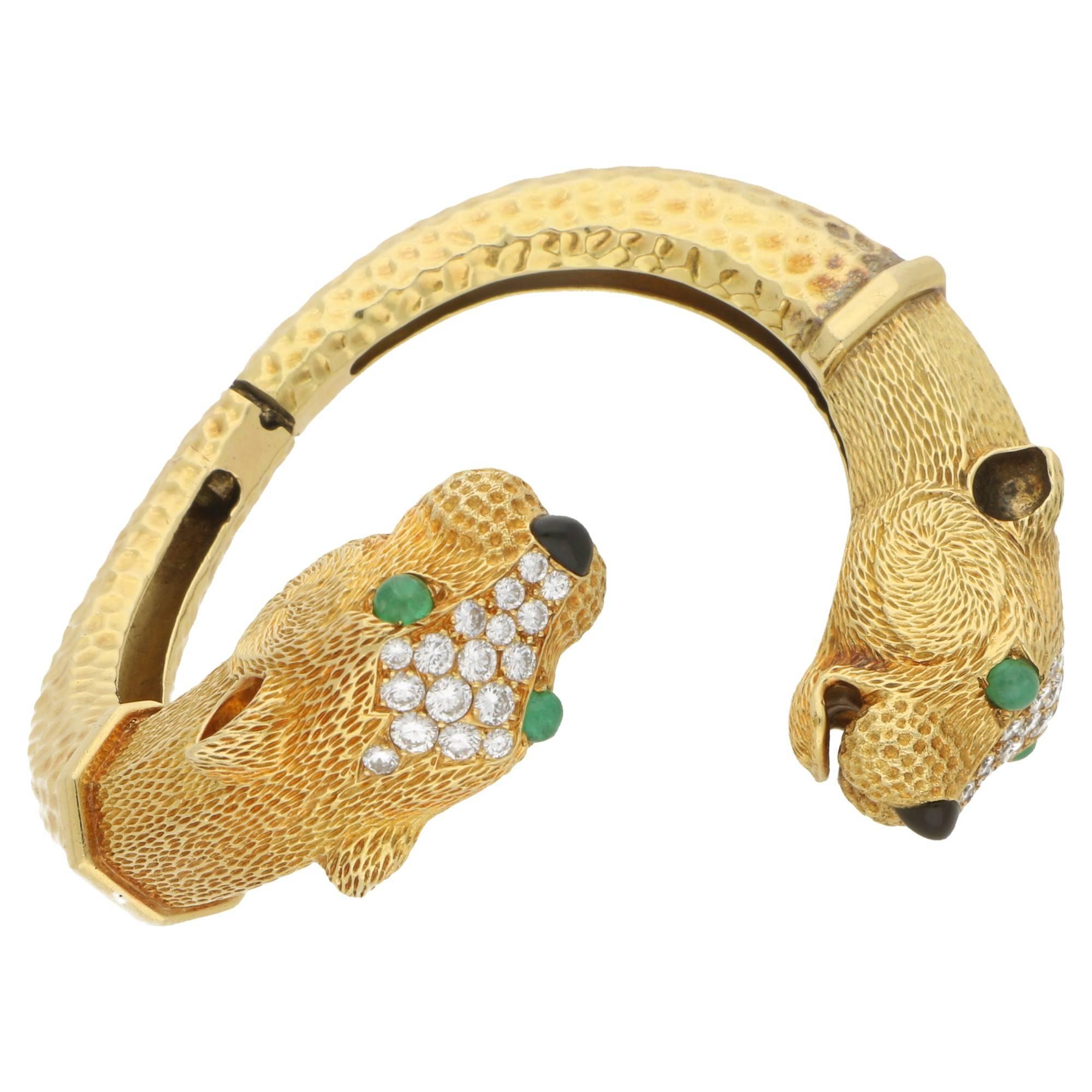 Estimated total emerald weight: 0.48cts. Estimated total diamond weight: 2.94cts. Assessed diamond colour: E-F. Assessed diamond clarity: VVS1. 
A truly sensational late 1960's double headed golden leopard bangle. 
Each fore-head is hand crafted