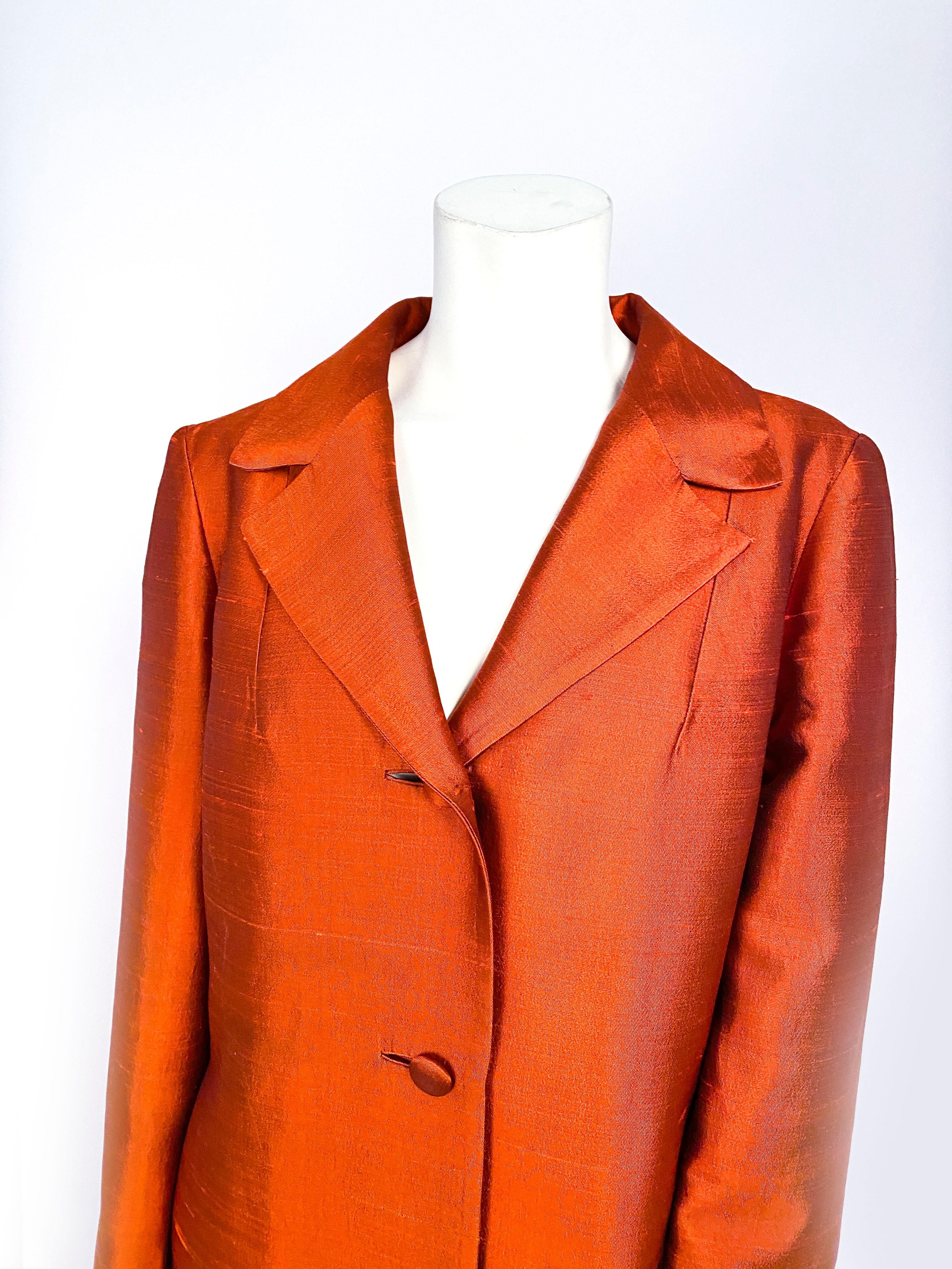 1960s Lilli Ann rust-colored coat in raw silk. The textile has an iridescence to add a reflective sheen. The face has covered buttons, inset button holes, invisible side pockets, peak lapels, anf full length sleeves finished with a faux cuff and