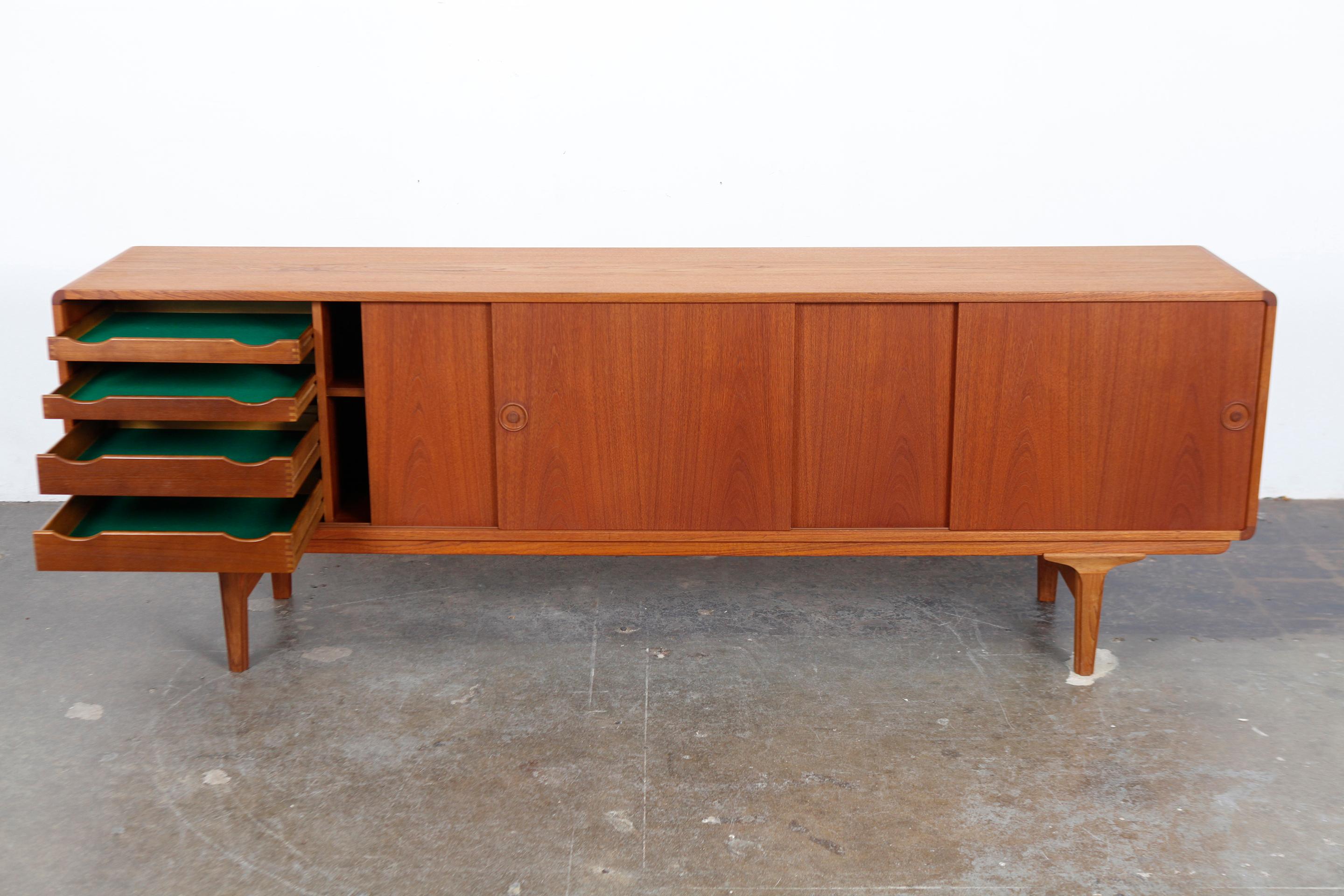 Danish 1960s long, low teak sideboard with 4 sliding door teak sideboard with very clean lines and subtle handles. Newly refinished in a natural teak oil finish. 1960s, Denmark.