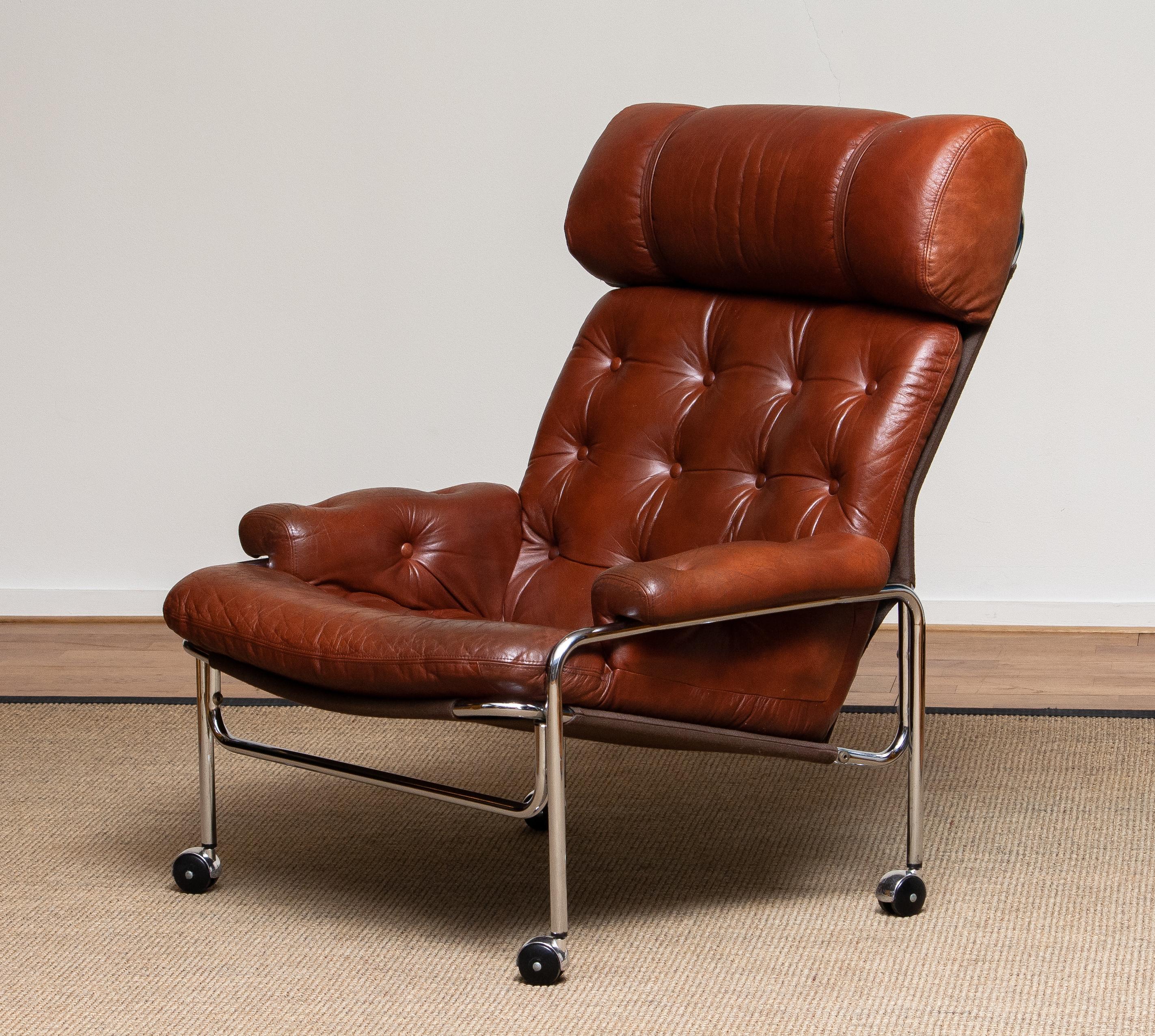 Beautiful lounge / easy chair in aged brown / cognac leather and chrome designed by Pethrus Lindlöfs for A.B. Lindlöfs Möbler Lammhult, Sweden. 
The aged leather on the chairs gives the chairs the typical vintage character. The leather is soft and