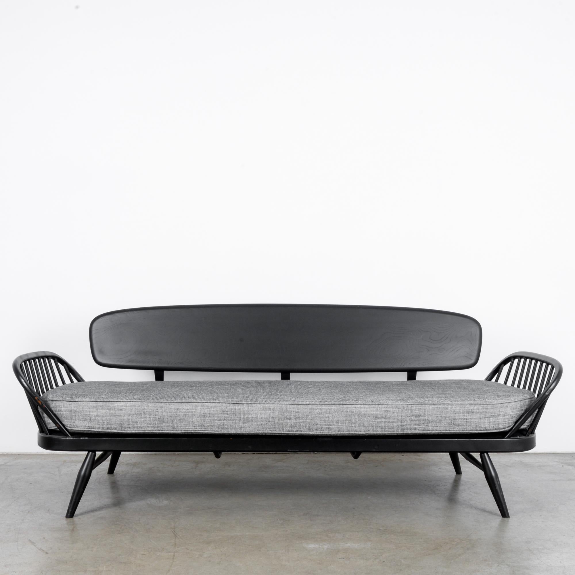 This sofa daybed designed by Lucian Ercolani was made in the United Kingdom, circa 1960. It comfortably sits three and also serves as a single bed for an overnight guest. Supported on splayed, turned legs, the daybed features curved armrests on the