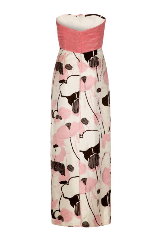 This opulent 1960’s strapless silk blend evening gown from Macphail Couture has a simple, elegant line and is in lovely vintage condition. The dress features an abstracted poppy print in sugar pink, soft grey and black on an ivory background which