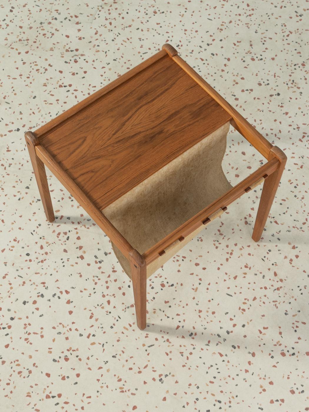 Wonderful magazine rack from the 1960s. Solid teak frame and a table top in teak veneer with a small magazine tray made of fabric.

Quality Features:
very good workmanship
high-quality materials
Made in Denmark, Design/manufacturer: S.P.