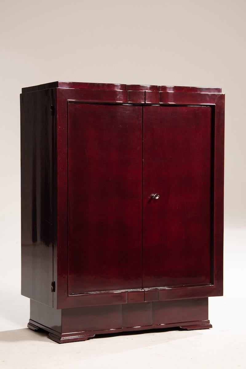 Mobile bar con ante in mogano e interni in legno naturale. Le porte si aprono a 180 gradi e all'interno ci sono spazi dedicati a bottiglie e bicchieri. Il coperchio superiore può essere aperto completamente, fornendo ulteriori funzionalità per