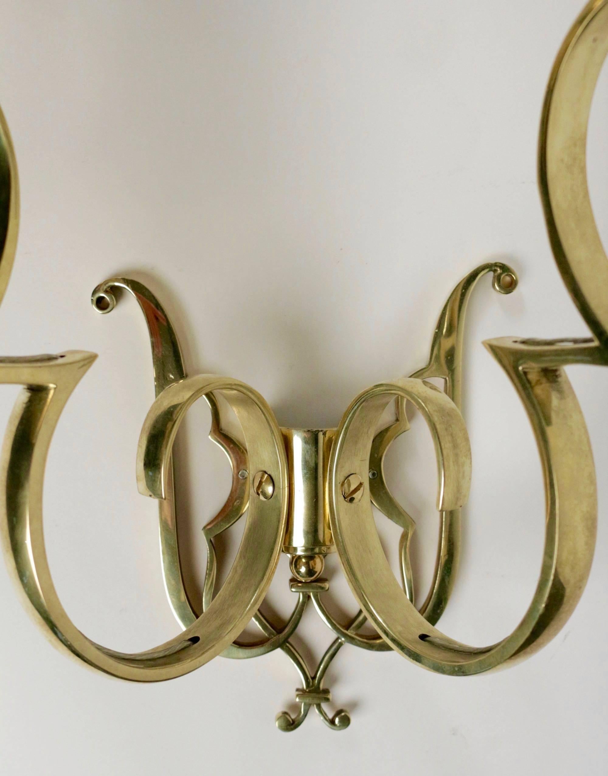 1960s Maison Honoré pair of brass sconce. 
Each sconce consists of two lighted arms with curves and counter curves. 
Back plate granted with the arms. 

Handmade lampshades, made of white ivory cotton. 

 