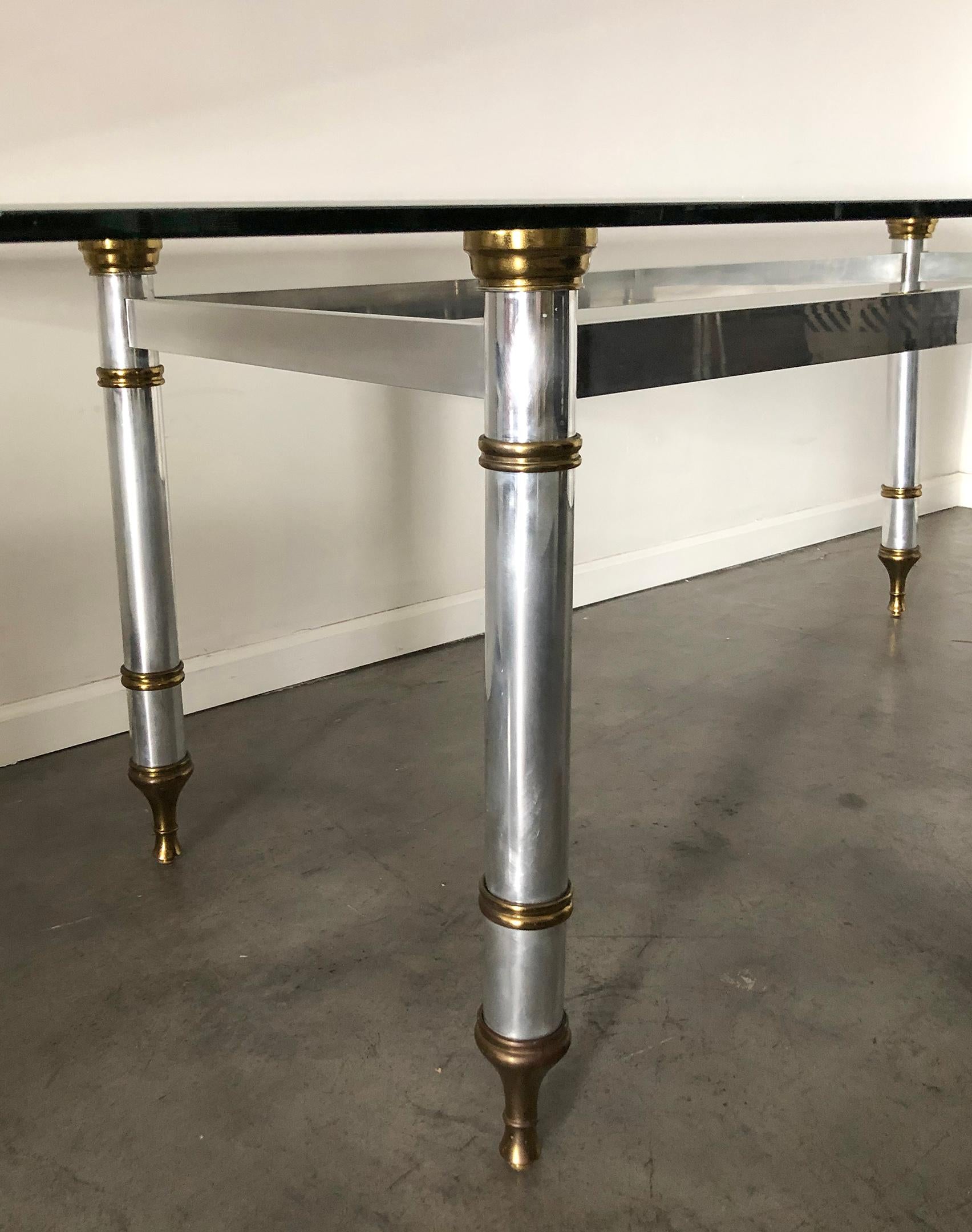 A 1960s steel and brass dining table. French designed Maison Jansen dining table exudes Hollywood regency and regency styling and is sure to compliment any fashionable environment.

This stunning table has such a modern look that it could