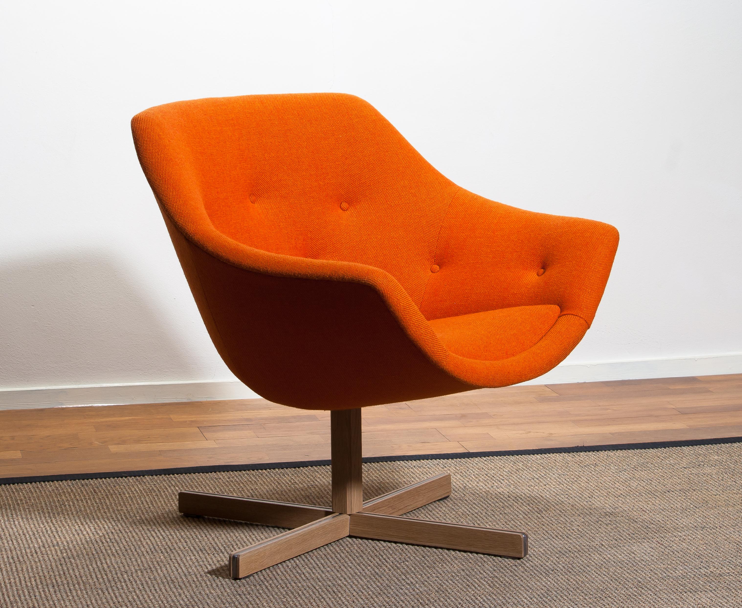 Fantastic 'Mandarini' swivel armchair made by Carl Gustaf Hiort for Puunveisto Oy, wood work Ltd. This chair is upholstered with a buttoned orange fabric 'Hallingdal' by Kvadrat designed by Nanna Ditzel, on an oak swivel base.
It is in perfect and