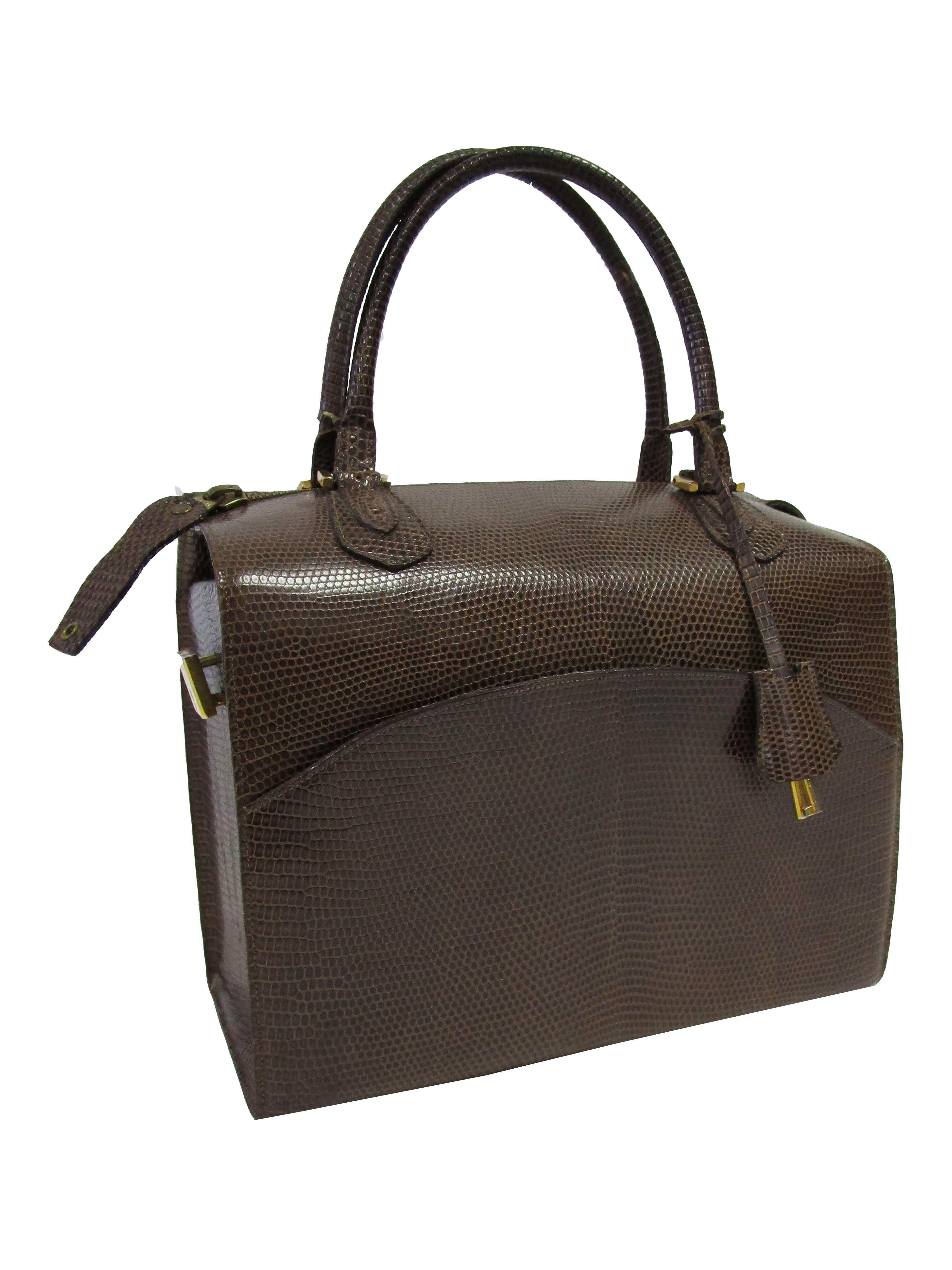 
Impeccably structured walnut brown lizard box purse from Martin Van Schaak!
This purse is reminiscent of a classic doctor's bag, with two top handles with a zippered opening in between. The exterior features a curved top stitched pocket. The purse