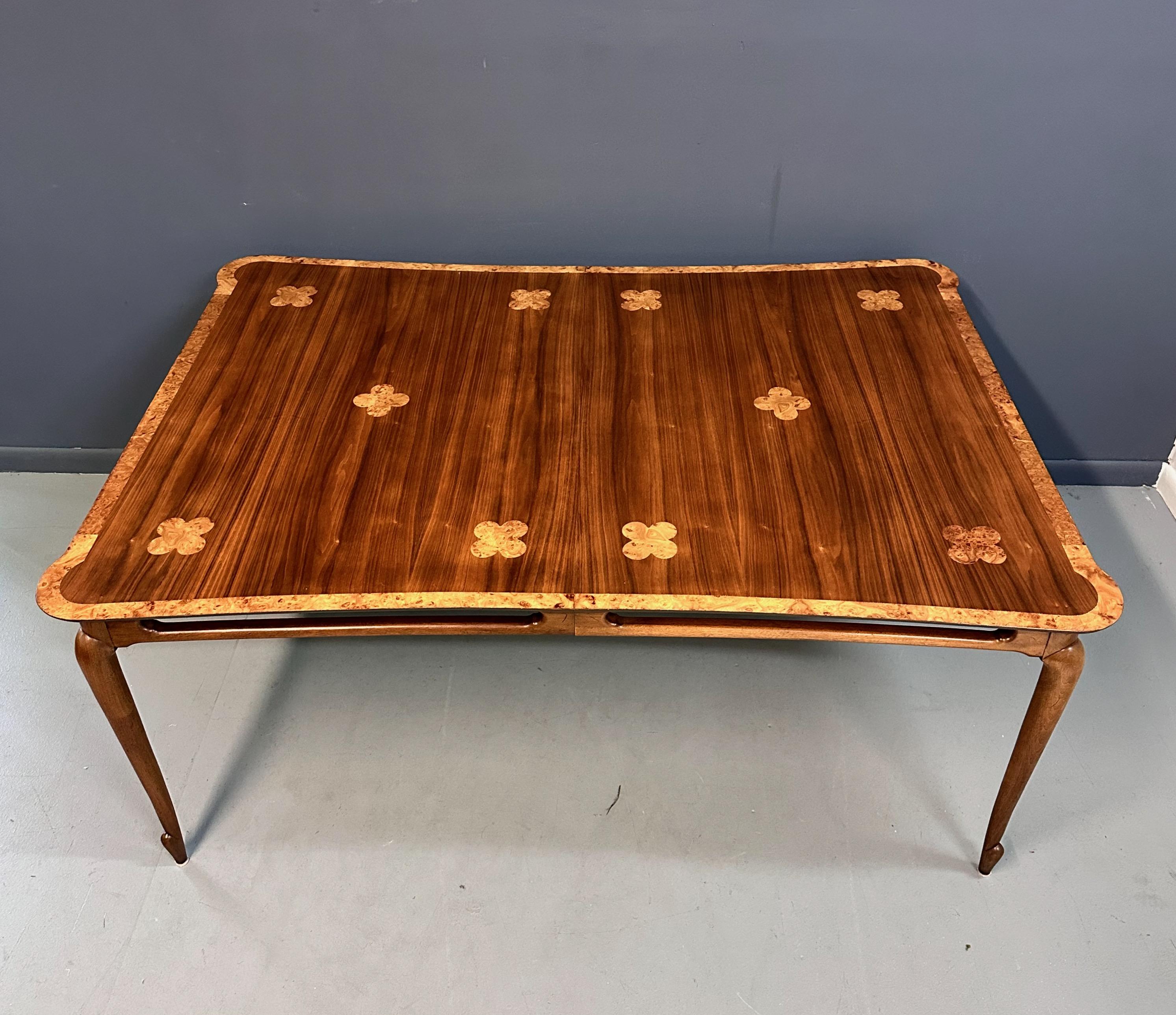 This 1960s Mastercraft Attributed Walnut Dining Table is exquisitely designed with burl accents and trim, showcasing expert craftsmanship and style. Constructed with quality walnut wood, this dining table has very interesting sculptural legs that