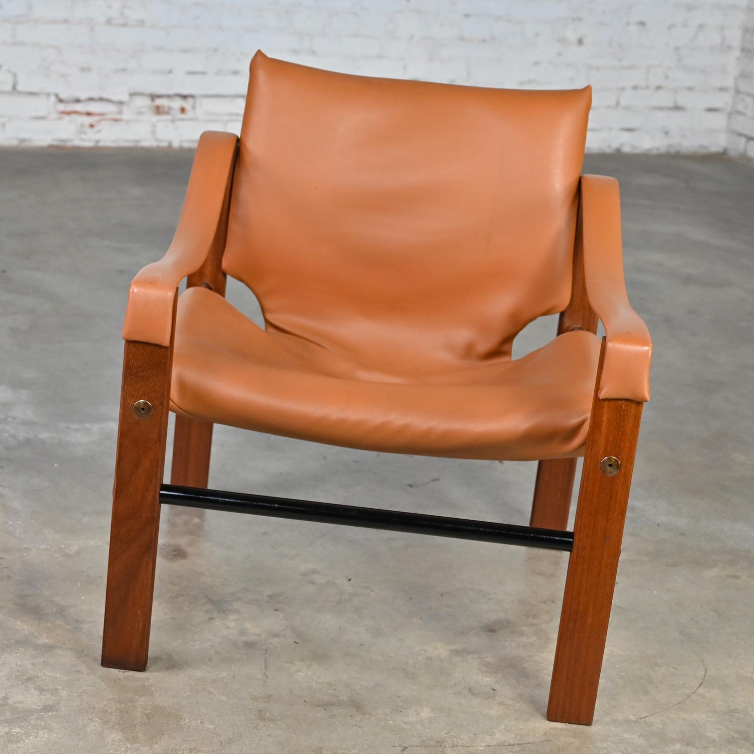 Fantastique chaise vintage Chelsea Safari Chair conçue par Maurice Burke pour Arkana Furniture, portant son faux cuir ou vinyle cognac d'origine avec un cadre en teck, des patins tubulaires en métal noir, et des détails de vis en acier.  Très bon