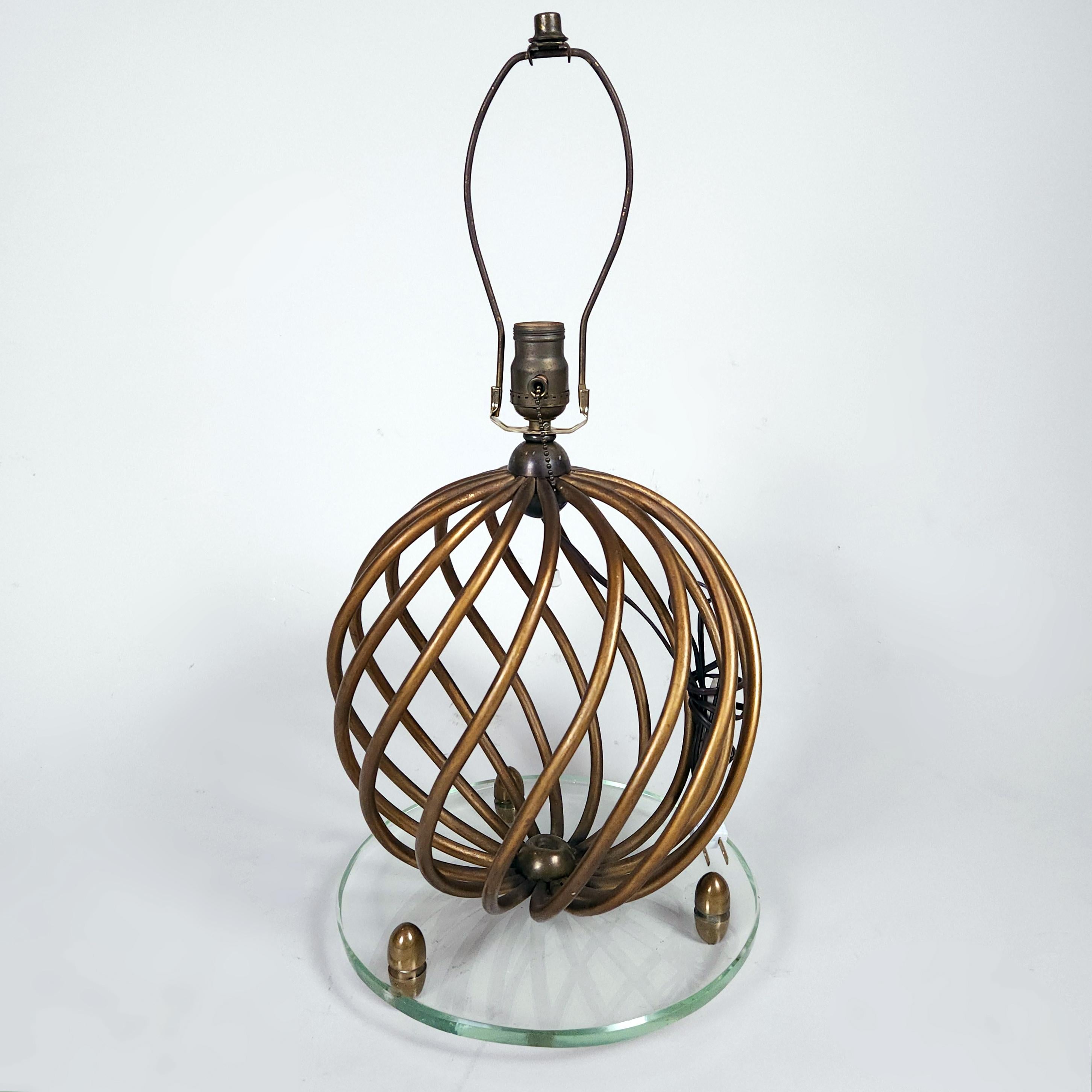 A Mexican 1960's gilt wrought iron table lamp in the style of Jean Royère. The sphere-shaped whirl design is set over its original glass base.