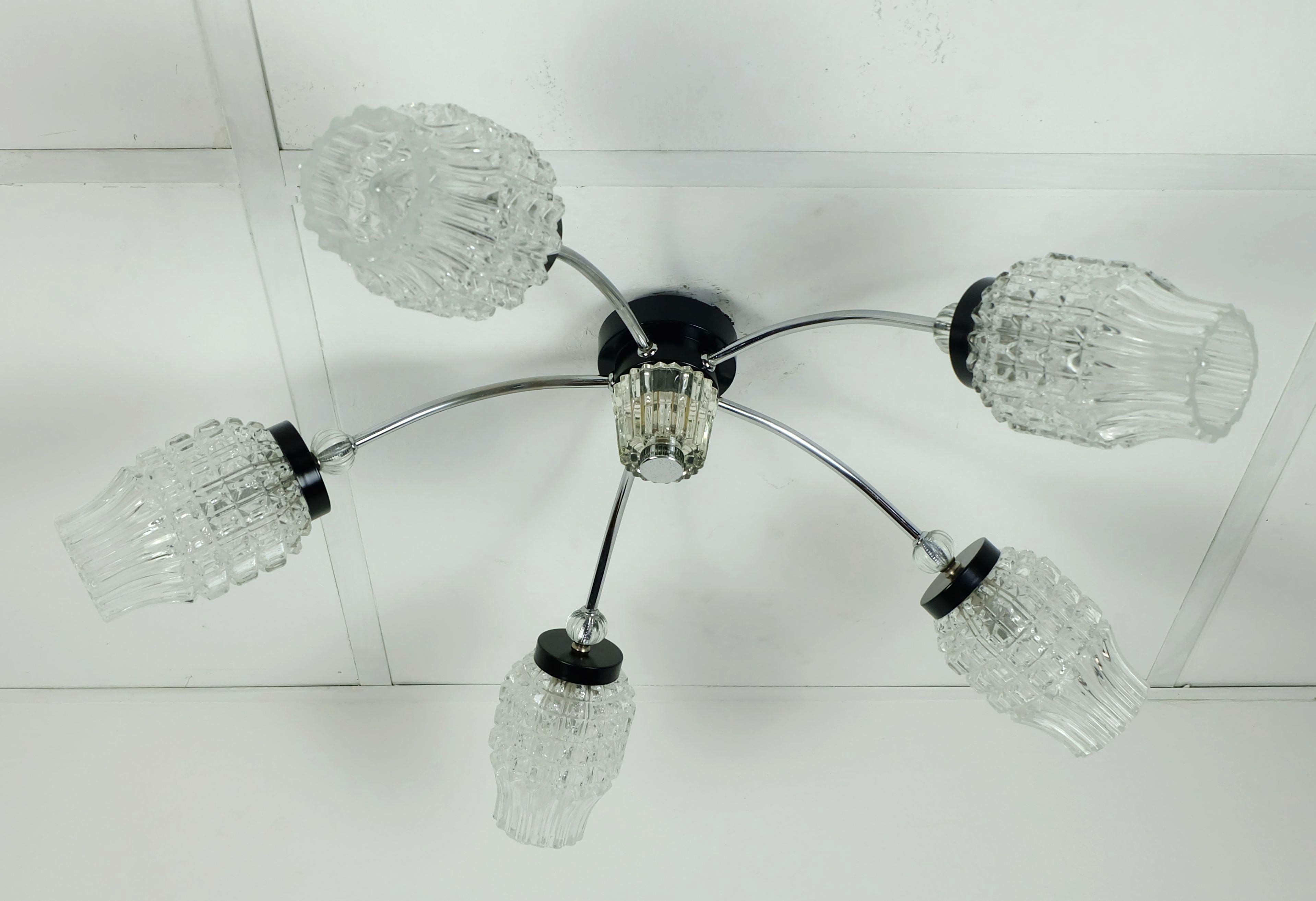 Un apparecchio da soffitto molto bello degli anni '60. Realizzata in metallo cromato e laccato nero. 5 bracci con paralumi in vetro, elementi decorativi anch'essi in vetro.

Il diametro è di 60 cm, l'altezza di 20 cm, i paralumi in vetro sono lunghi