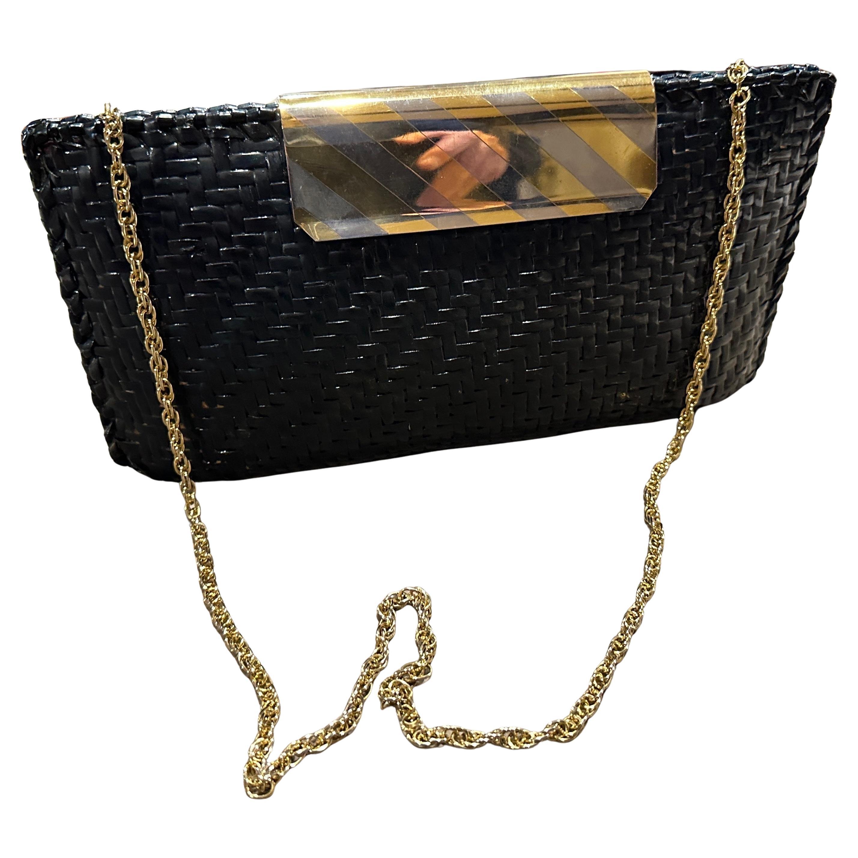 Questa elegante borsa da sera italiana del Mid-Century degli anni '60 presenta una sorprendente combinazione di texture e materiali. Il corpo della borsa è realizzato in vimini nero intrecciato, creando una superficie sofisticata e sottilmente