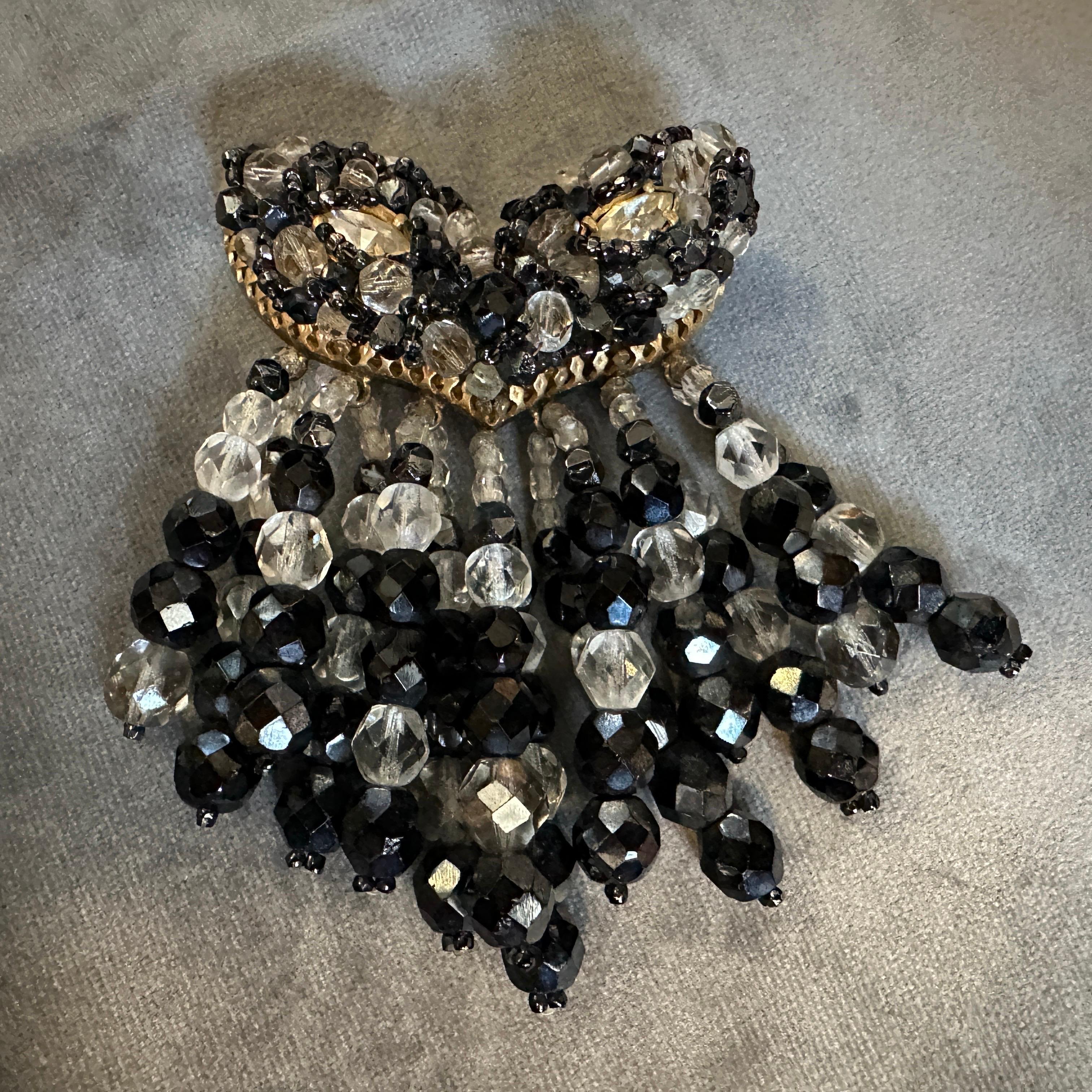 This exquisite Italian costume jewelry brooch from the 1960s is a captivating example of mid-century costume jewelry, blending theatrical elegance with bold design. Featuring a dramatic combination of faceted black and clear beads, it forms an